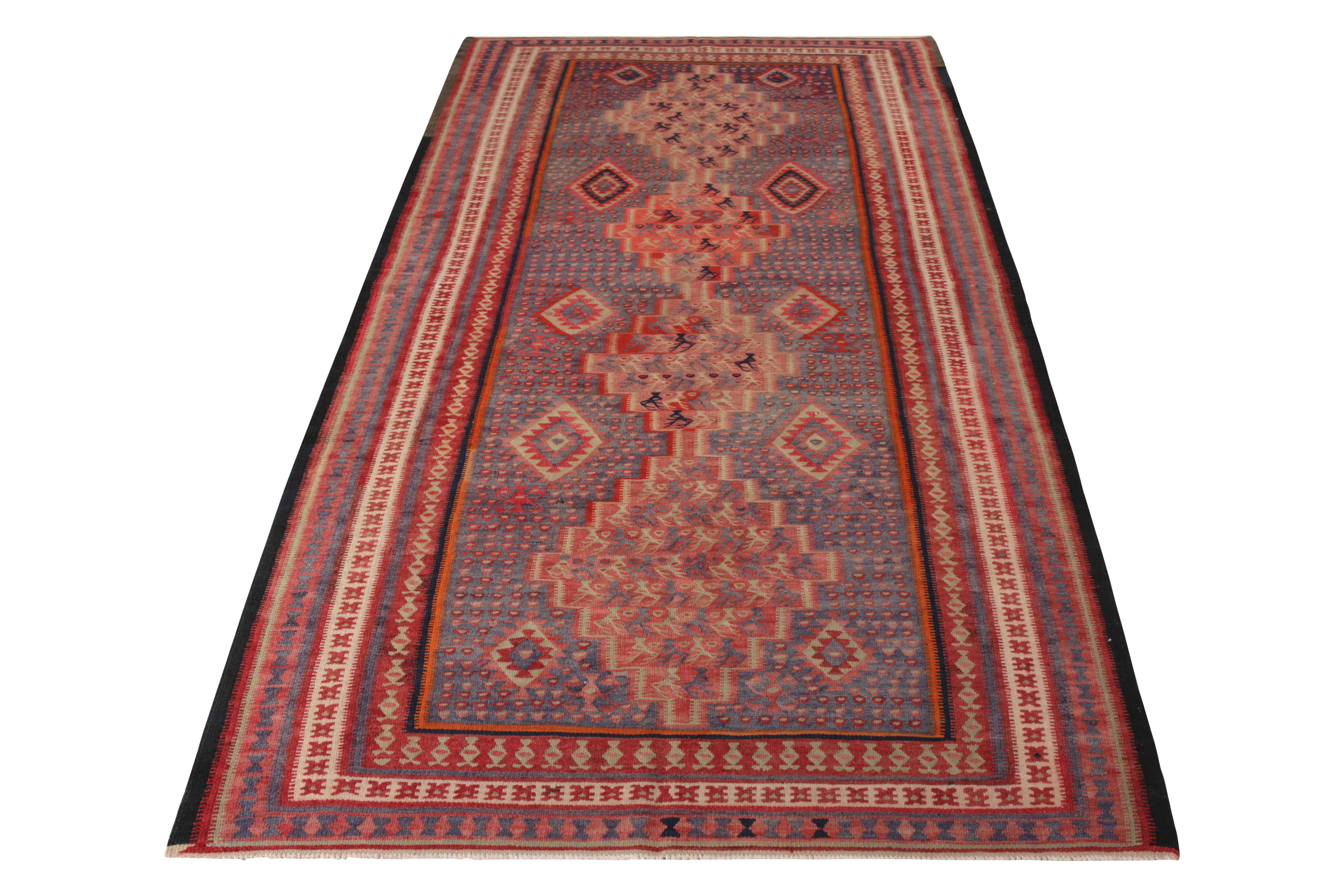 A 4x9 vintage Persian Kilim of Senneh rug design, handwoven in wool originating circa 1950-1960. Enjoying a uniquely graphic series of motifs filling the medallion pattern, playing fabulously against predominant reds and blues. Exemplifying the
