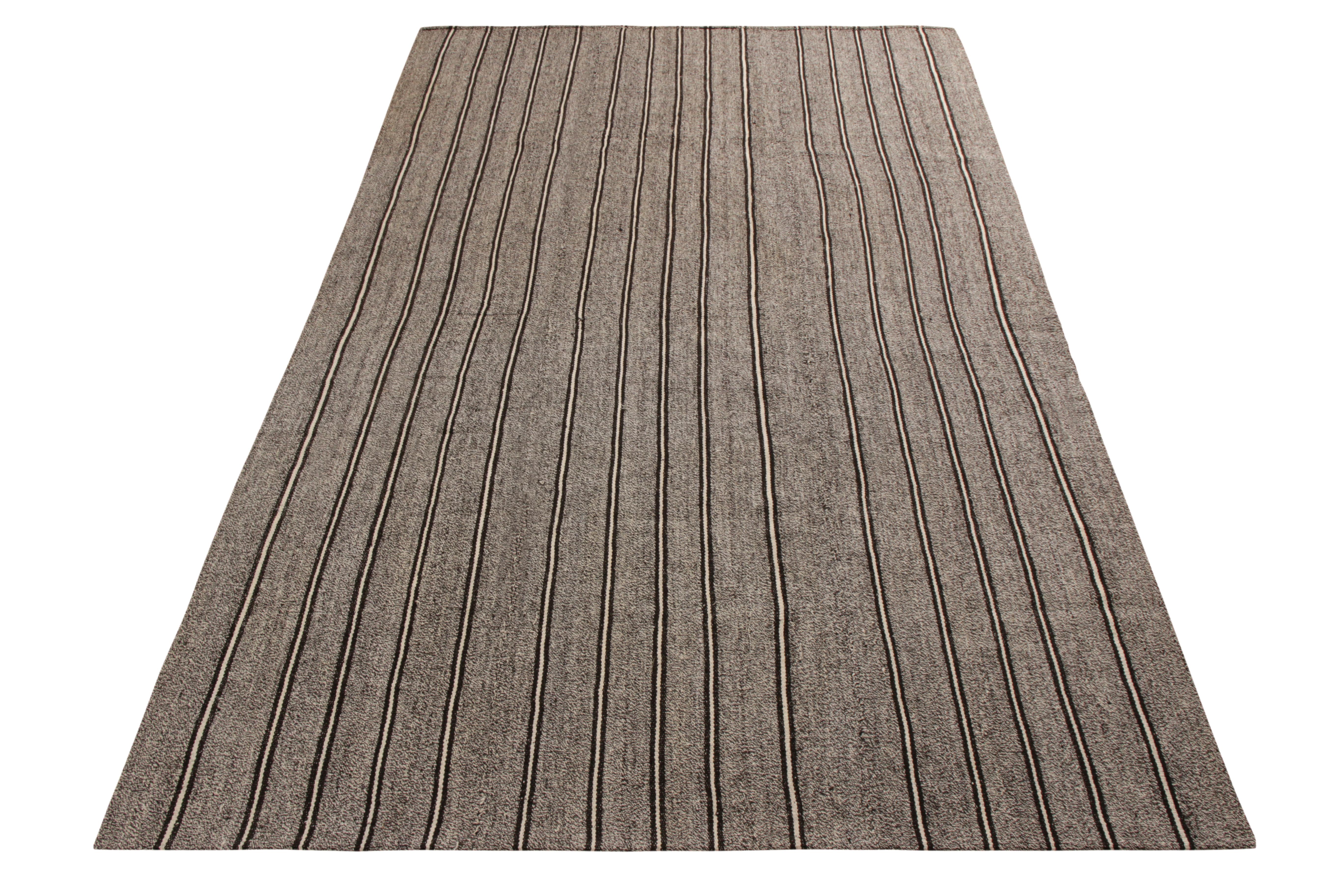 A vintage 5x7 Kilim rug in handwoven wool, originating from Turkey circa 1950-1960. Enjoying a forgiving, versatile gray with black and white stripes, connoting a sought-after paneled weaving style among mid-century Kilims. Further enjoying good