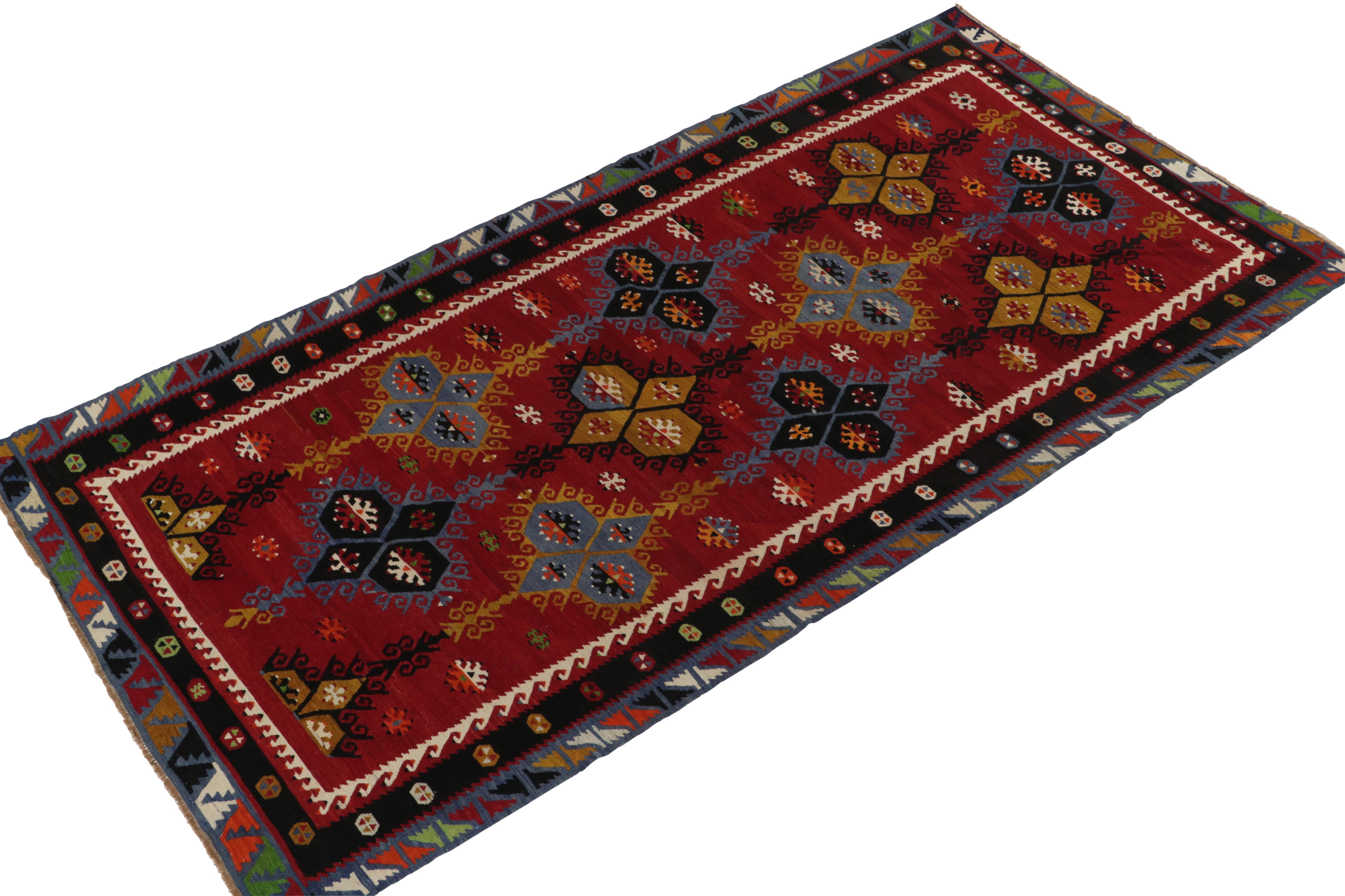 A vintage 6x10 Kilim rug, handwoven in wool originating from Turkey circa 1950-1960. Enjoying a play of tribal motifs and medallions, marrying vividly bright colors against rich red and black for a bold presence underfoot. A uniquely sized piece
