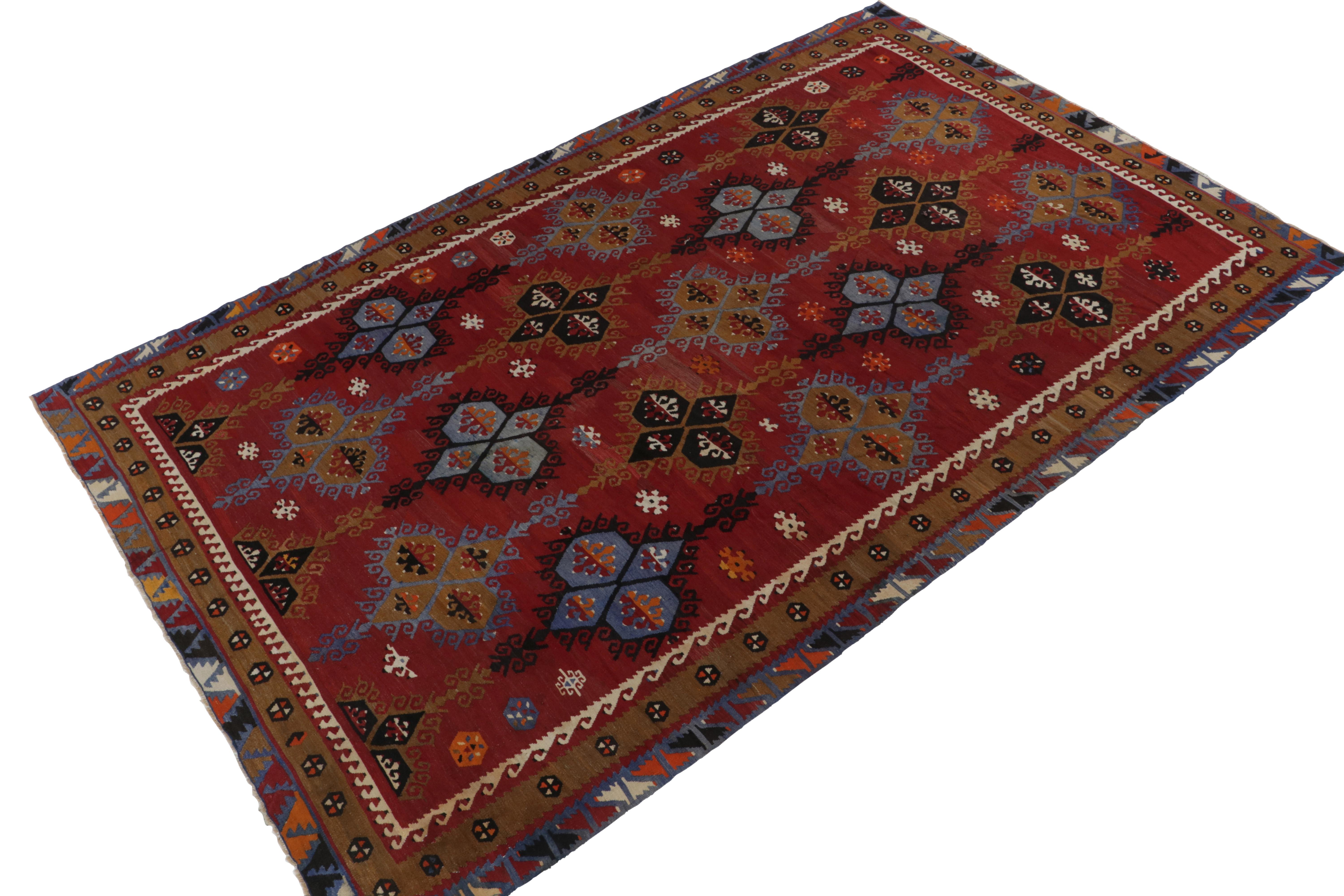 A vintage 7x12 Kilim rug, handwoven in wool originating from Turkey circa 1950-1960. Enjoying a play of tribal motifs and medallions with an especially present, cool blue marrying rich red and brown in the prevailing colorway for a unique presence