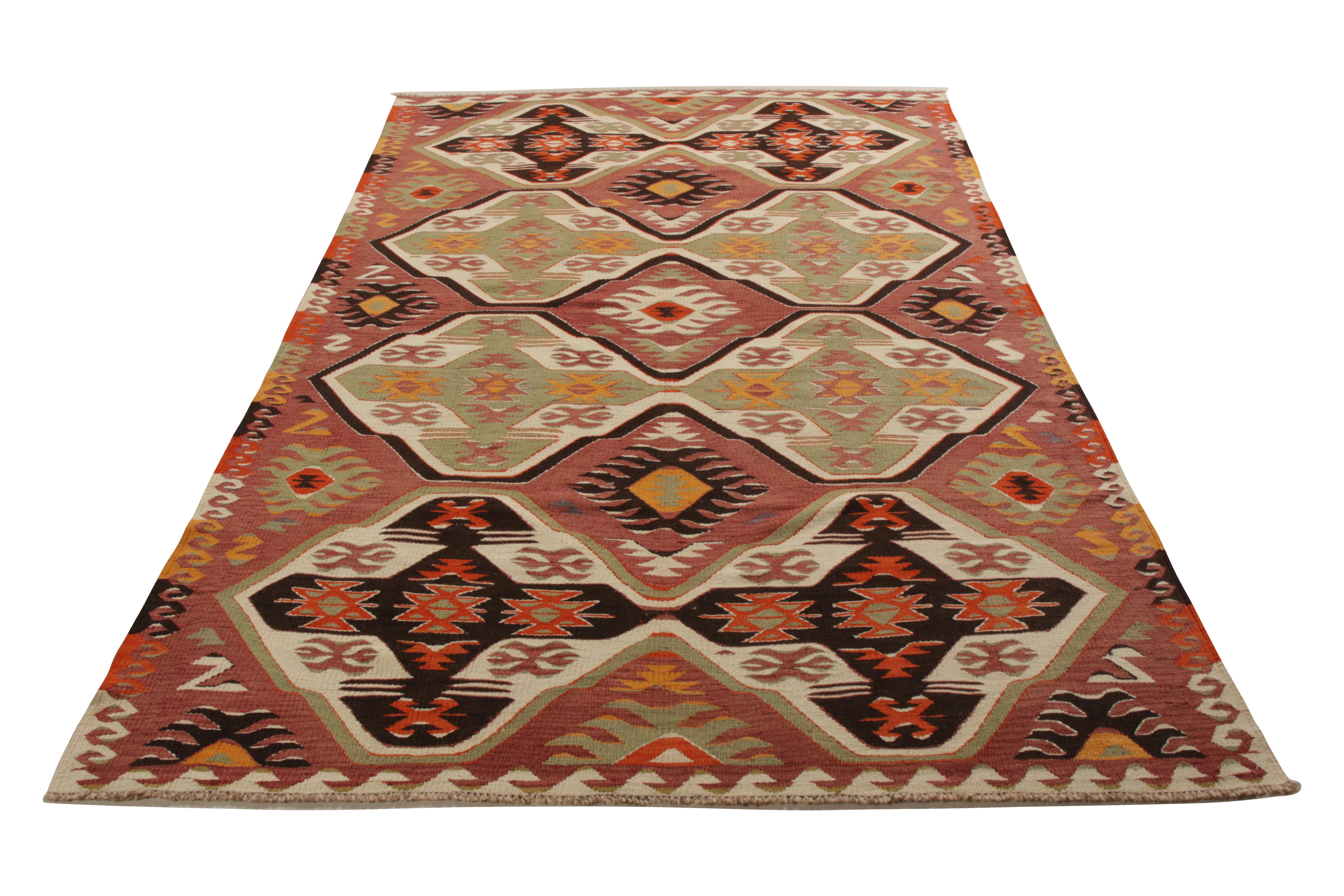 A 6x9 vintage Kilim rug, hand woven in wool originating from Turkey circa 1950-1960. Enjoying a unique near-black accent to red-pink and green hues complementing the all over geometric pattern. Idyllic in symmetry, exemplative of the midcentury