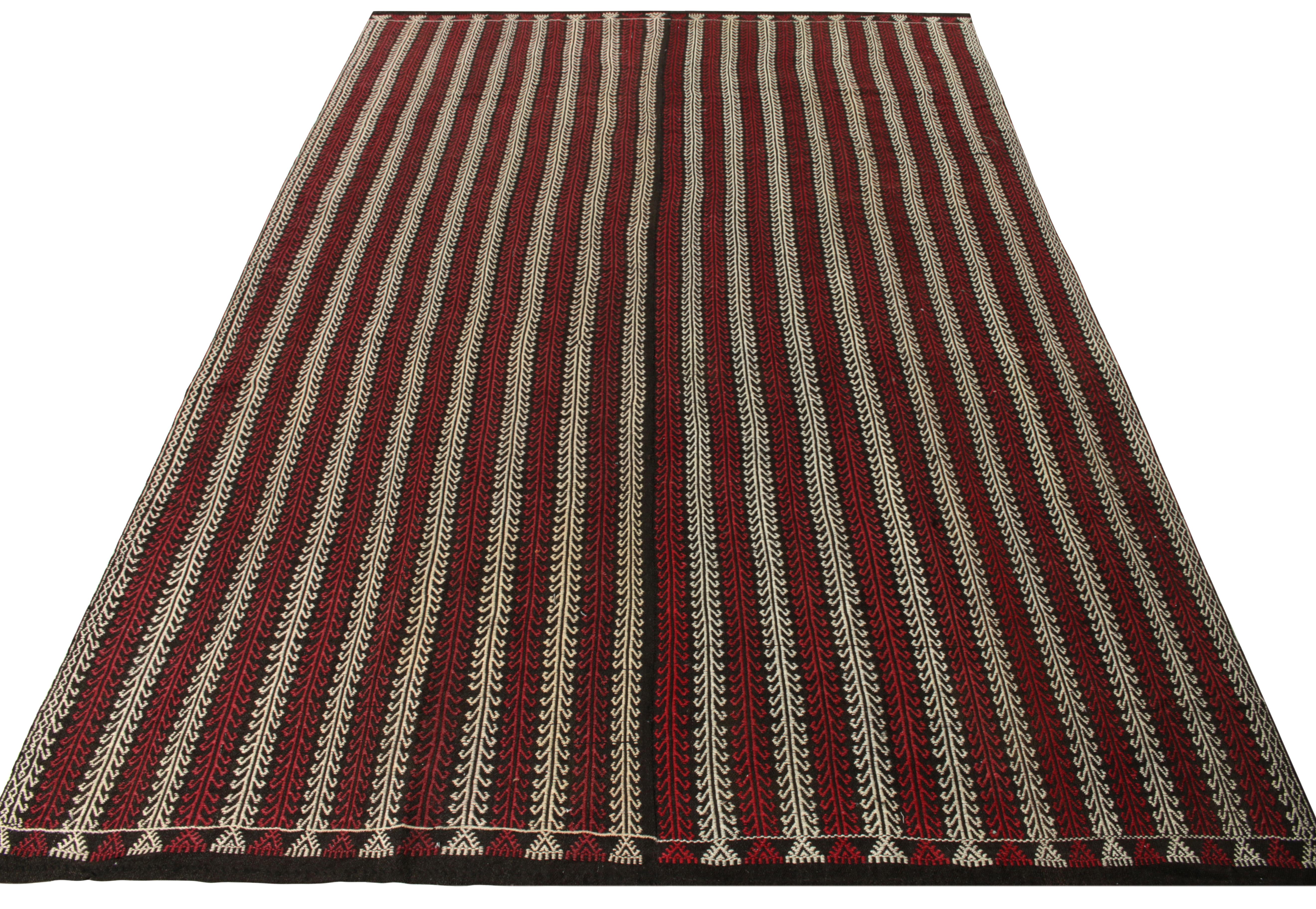 Hailing from Turkey circa 1950-1960, a mature vintage kilim rug enjoying a symmetric geometric pattern branching symmetrically for a strong sense of movement - highlighted with rich red and white on a charcoal black scale. Enigmatic yet elegant, a
