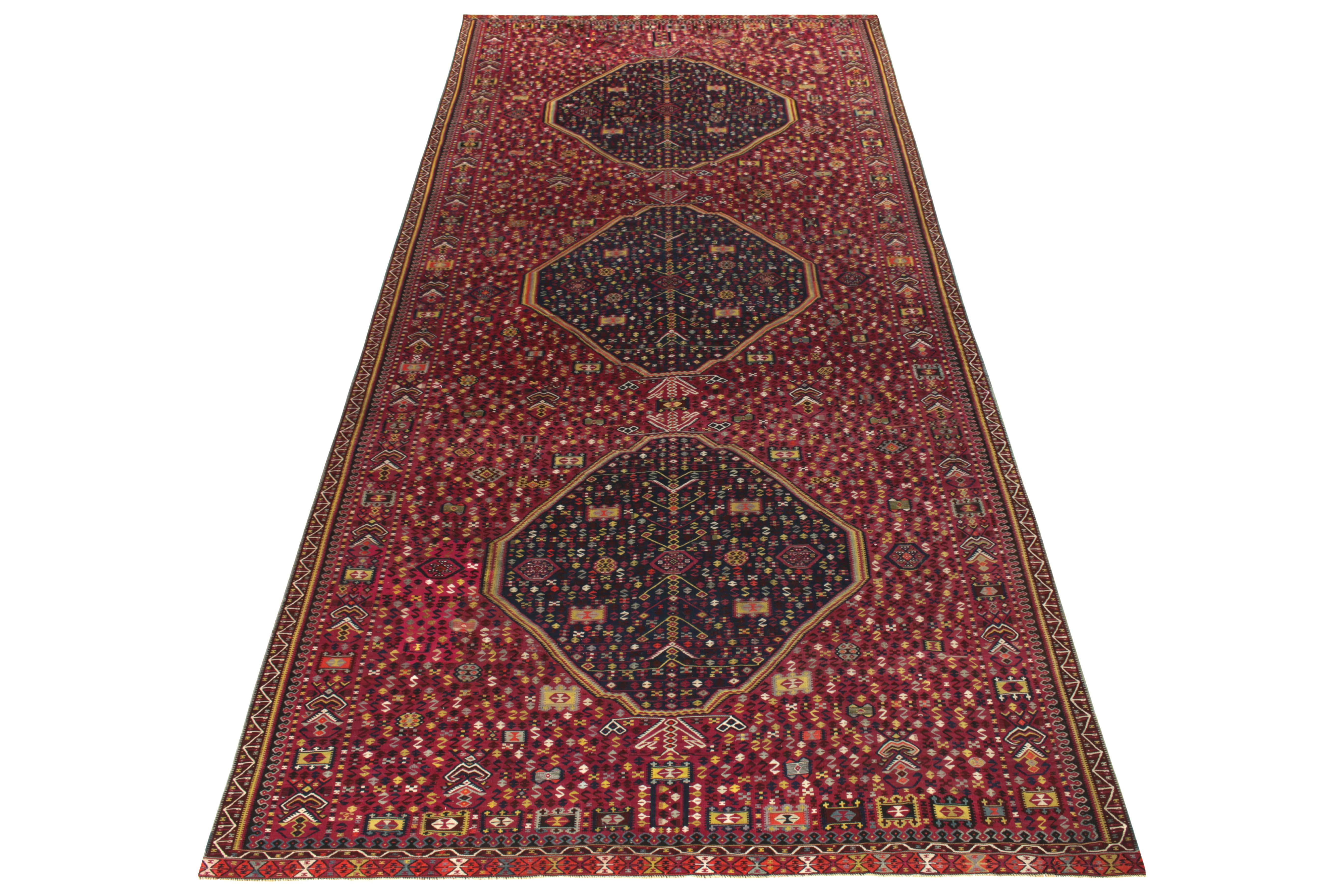 A rare gallery size vintage kilim rug originating from Turkey circa 1950-1960. The classic rendering carries an archaic demeanor in a luscious maroon and royal blue geometric pattern—exemplifying the celebrated Turkish aesthetics that manifest as