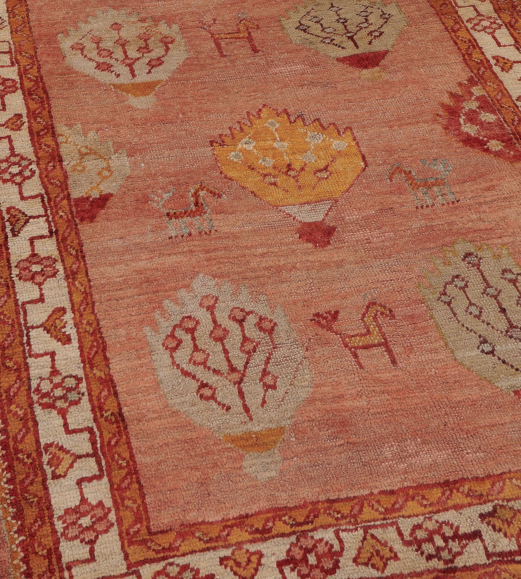 This antique Oushak runner has a soft terracotta-red field with ivory, brick-red and golden-yellow shield shaped lozenges and part-lozenges each containing angular floral vine with angular horse-motifs at each side and above, in an ivory border of