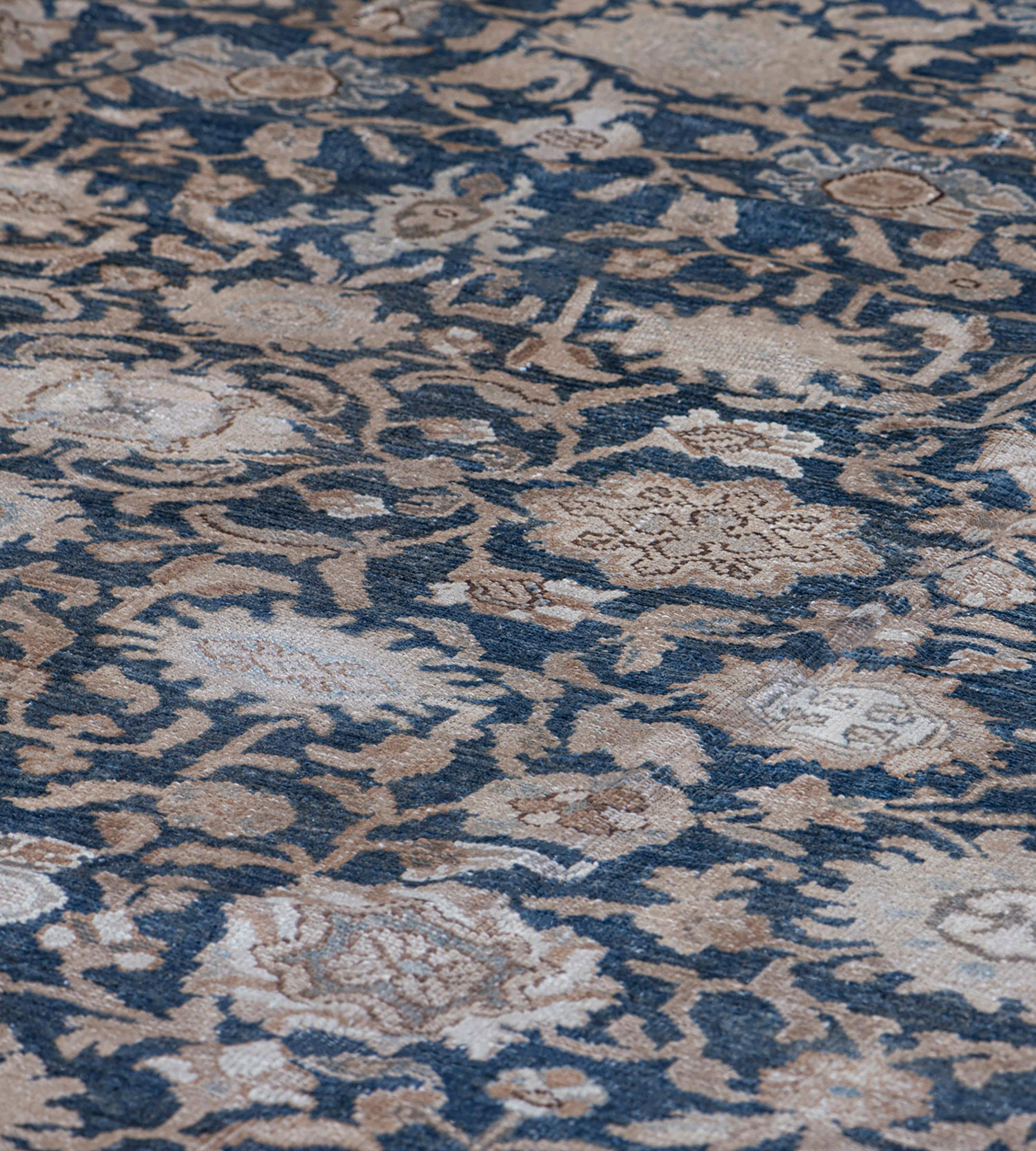 Ce tapis traditionnel persan Malayer tissé à la main présente un champ d'ensemble indigo de palmettes en pendentifs émettant un réseau dense de vignes fleuries, dans une bordure de palmettes à volutes beige impérial, entre des bandes de vignes