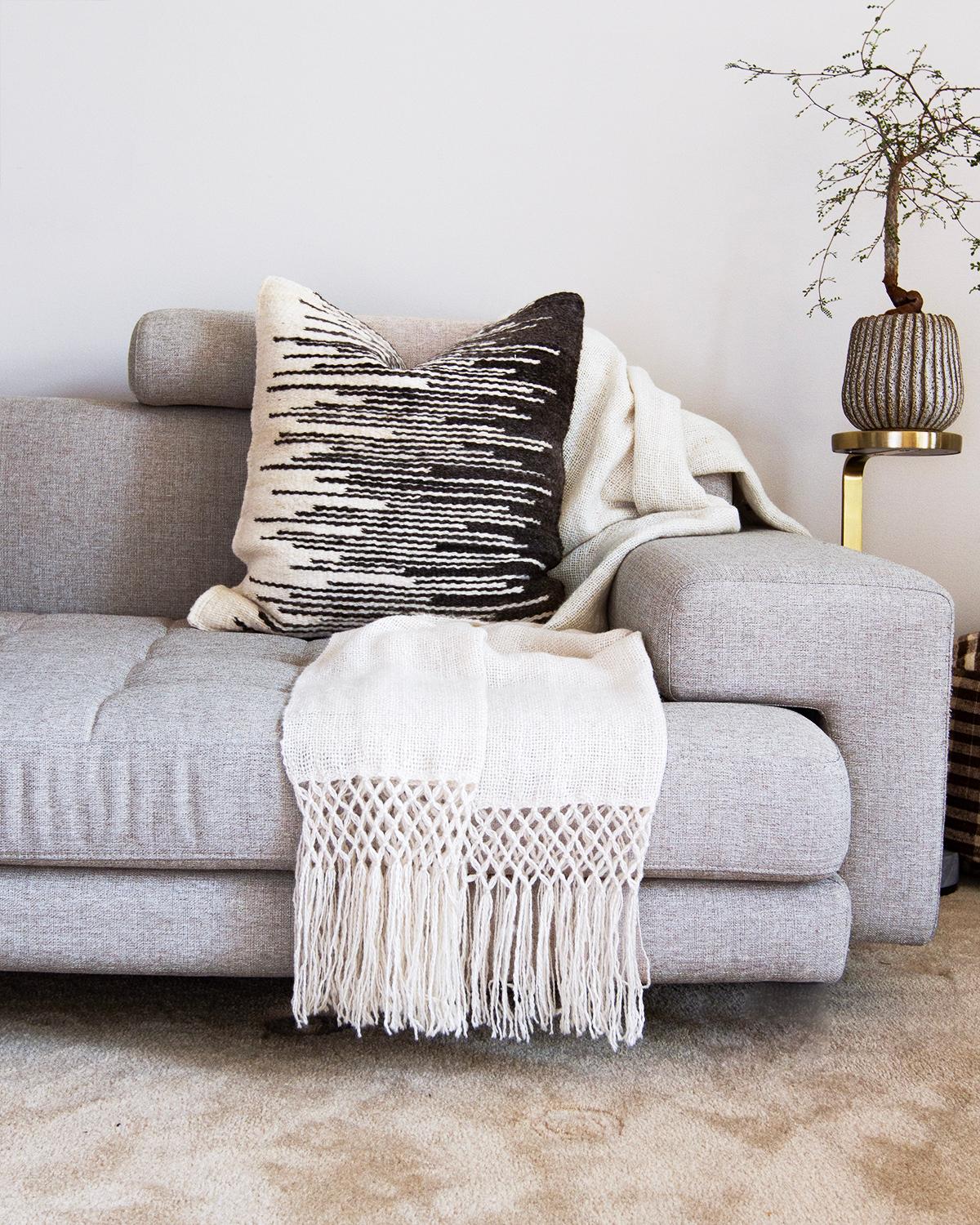 Questo cuscino Awanay Tango bianco e nero è l'aggiunta perfetta all'arredamento della tua casa. Realizzato a mano con lana di pecora di provenienza locale, presenta un design artigianale e intrecciato a mano, perfetto per un salotto contemporaneo o