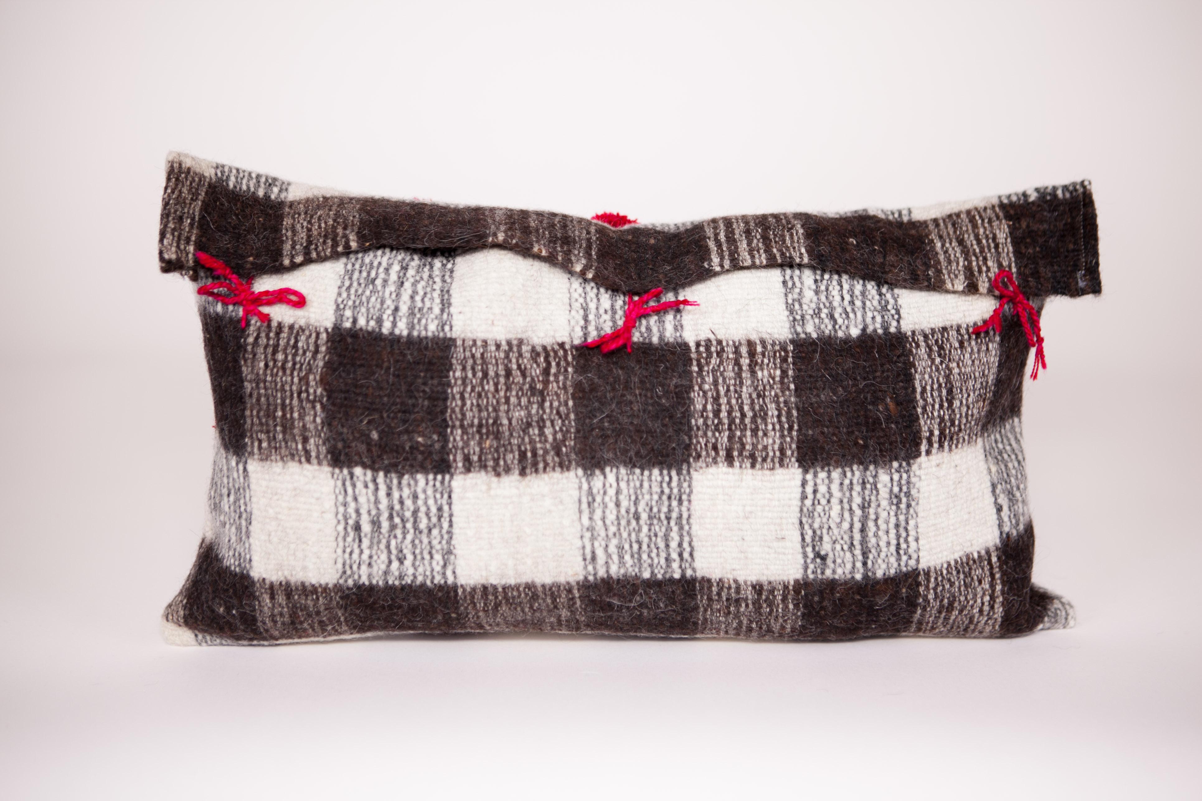 white pillow with black pom poms
