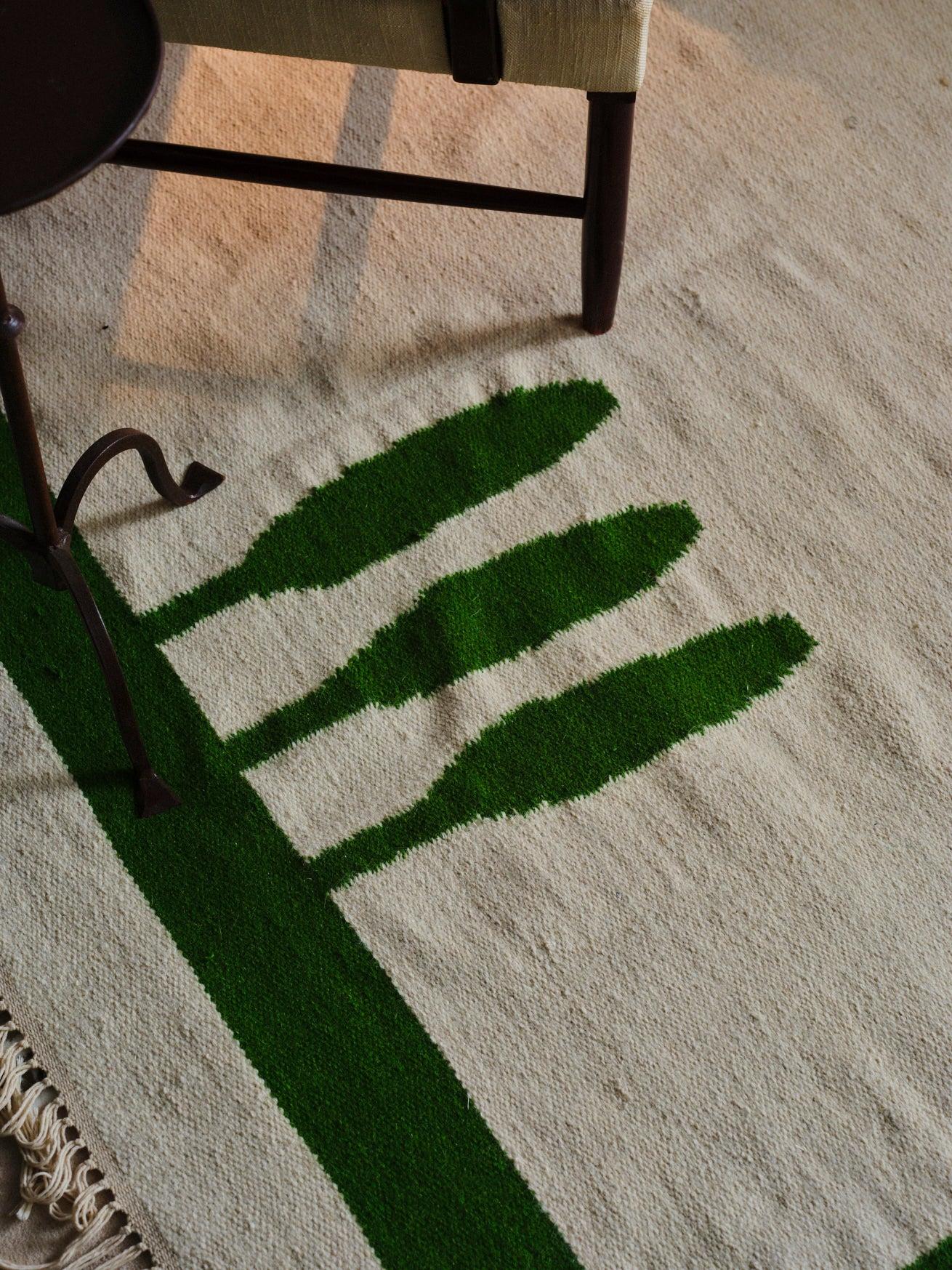 Dieser handgewebte Wollteppich ist ein dekoratives Stück, das die Gelassenheit und den Charme des mediterranen Stils heraufbeschwört. Sein Design zeichnet sich durch einen eleganten Rahmen in Grüntönen aus, die an die Farben der mediterranen