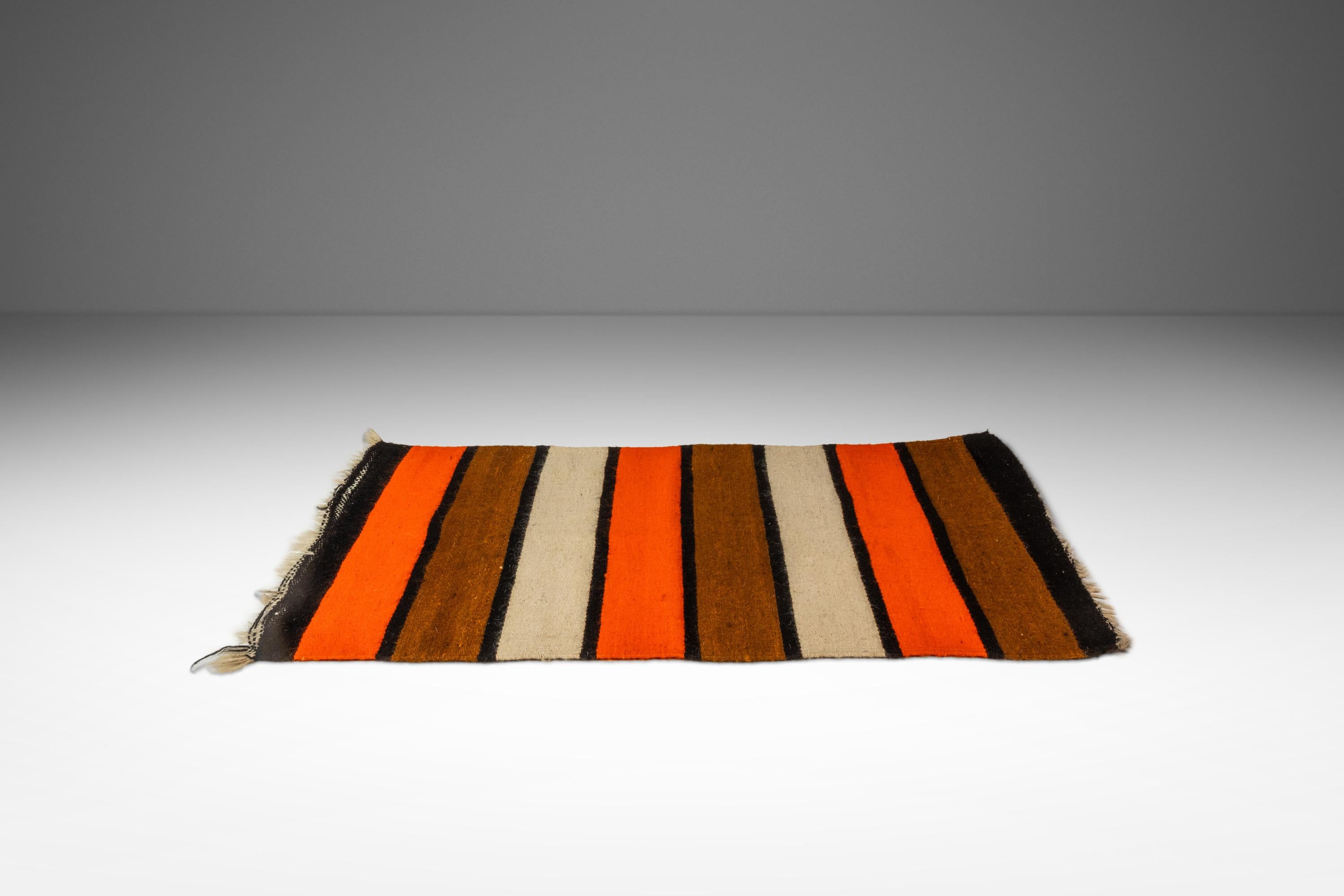 Diese charmante Vintage-Satteldecke aus den 1950er Jahren ist ein rustikales und vielseitiges Stück amerikanischer Handwerkskunst. Die Decke ist mit einer reichen Mischung aus erdigen Tönen und kühnen geometrischen Mustern gewebt und weist die für