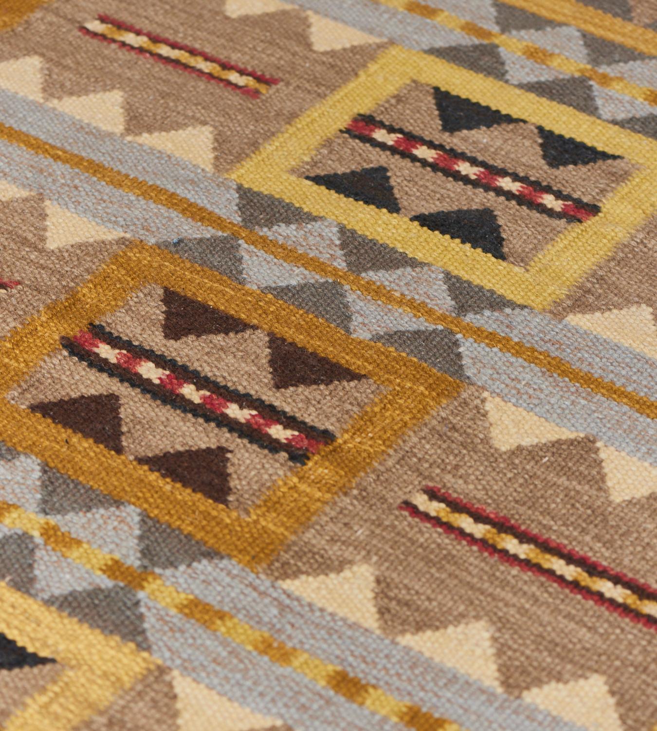 Ce tapis de style suédois tissé à la main présente un champ central composé de six bandes horizontales de cinq panneaux carrés avec un contour jaune sable nuancé renfermant des losanges partiels appariés brun chocolat au-dessus et en dessous,