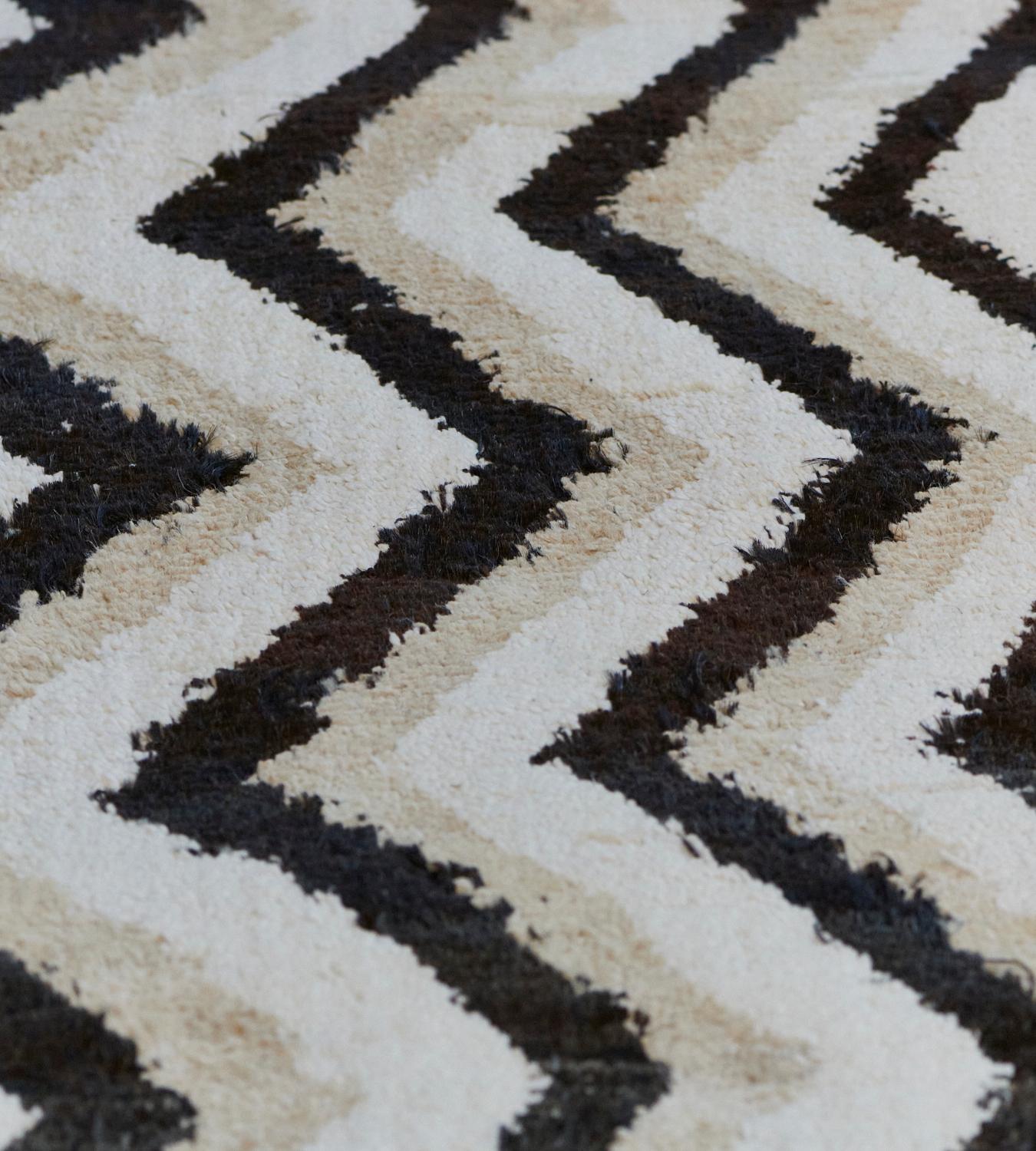 Dieser handgewebte, mittelflorige türkische Deco-Teppich hat vertikale Zickzackstreifen in Beige, Elfenbein und Anthrazit. Dieses Design aus der Mansour Modern-Kollektion wird von Meisterwebern unter Verwendung der besten Qualitätstechniken und