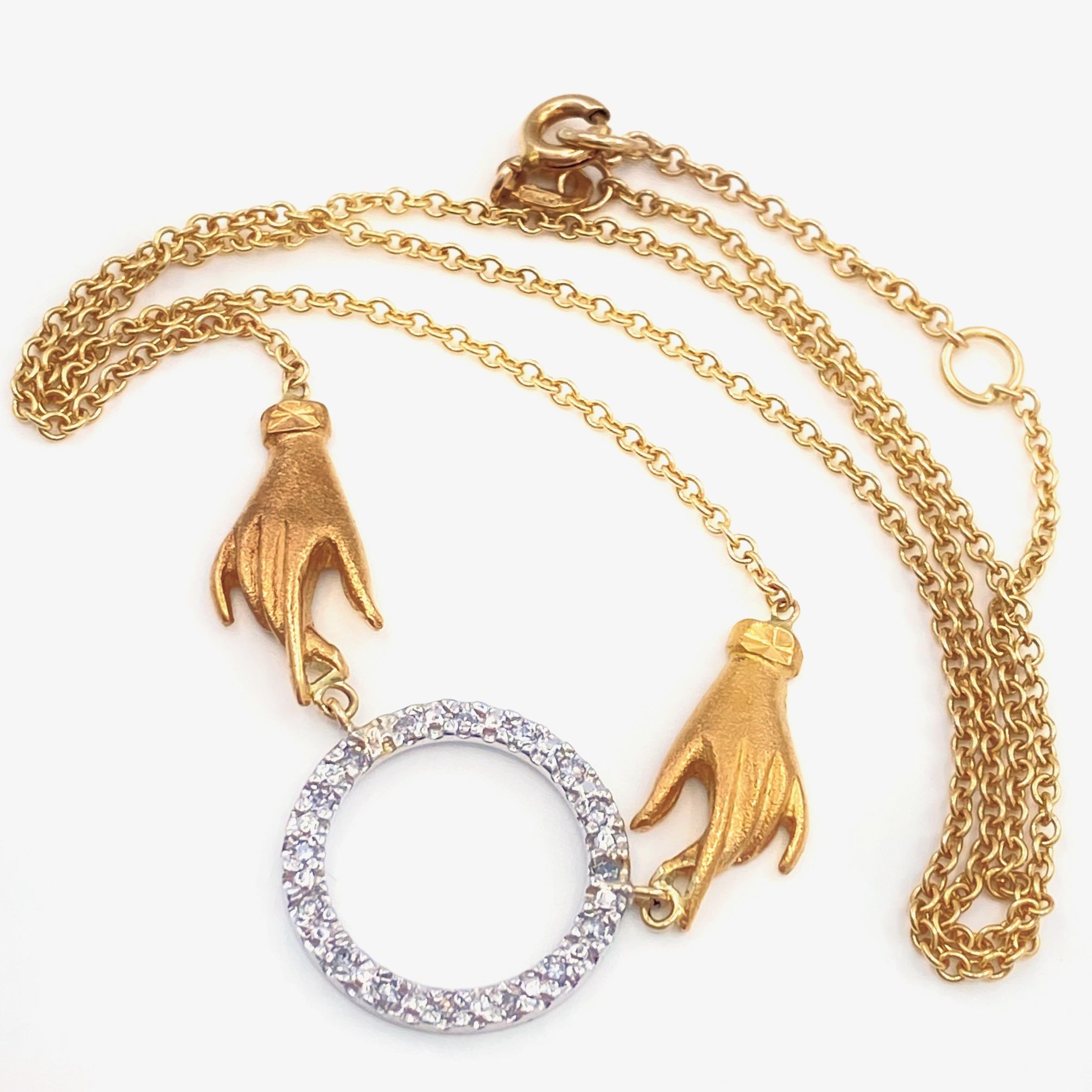 This one-of-a-kind assembled piece was cooked up by Eytan Brandes using vintage components.  

The 18 karat yellow gold hands, with their cuffed gloves and frosty finish, are two of about a dozen hand charms acquired in a kooky mixed lot from a