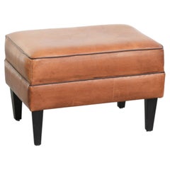 Pratico pouf in pelle di pecora dai colori caldi, rifinito con bordino nero