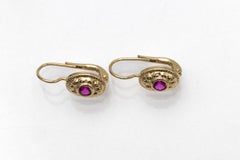 Hanging 14-karat gold earrings with an oval element set with a synthetic ruby
