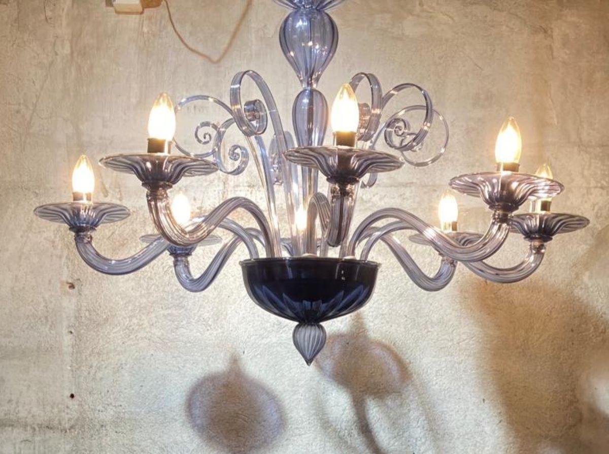 Grande ed elegante lampadario in vetro di Murano a 8 luci.
I bracci del lampadario sono rivolti verso l'alto, con le 8 lampadine a vista.
Lampadario perfettamente funzionante.
 