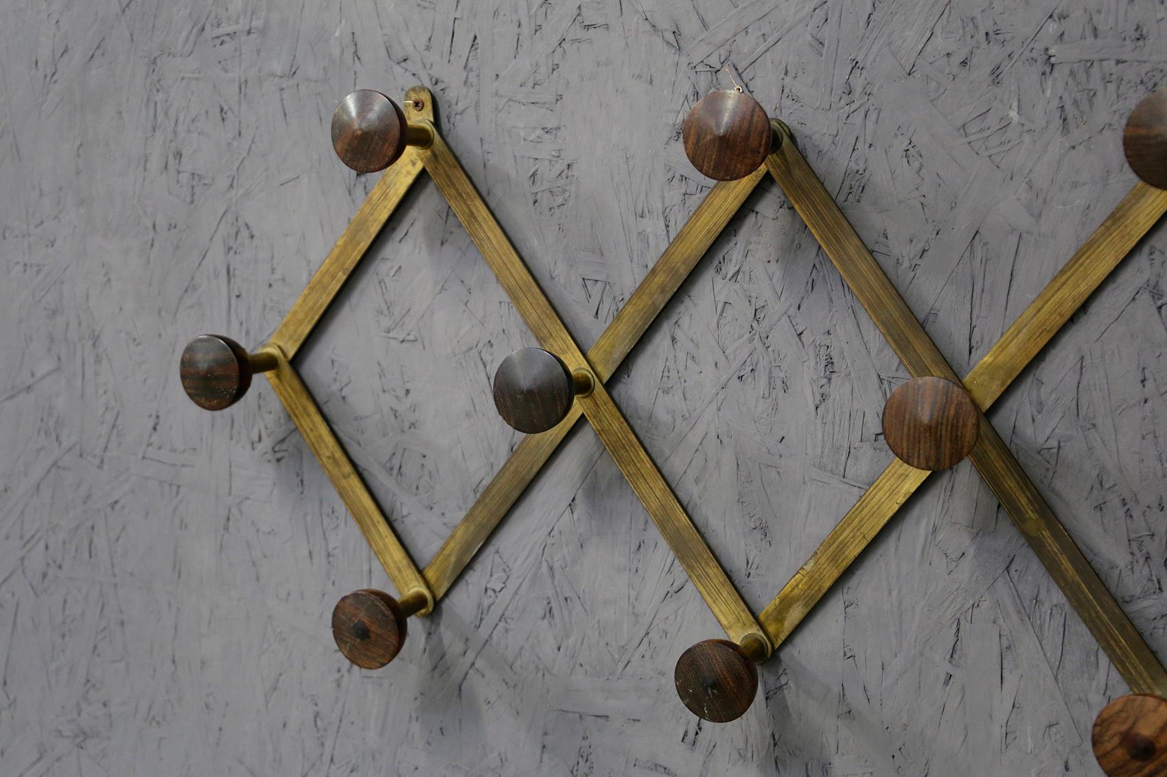 Elegant clothes hanger designed by Luigi Caccia Dominioni from 1950. The structure of the clothes hanger is in brass. The object is adjustable and extendable in width with accordion opening. Its ten knobs are made of wood. The clothes hanger is in