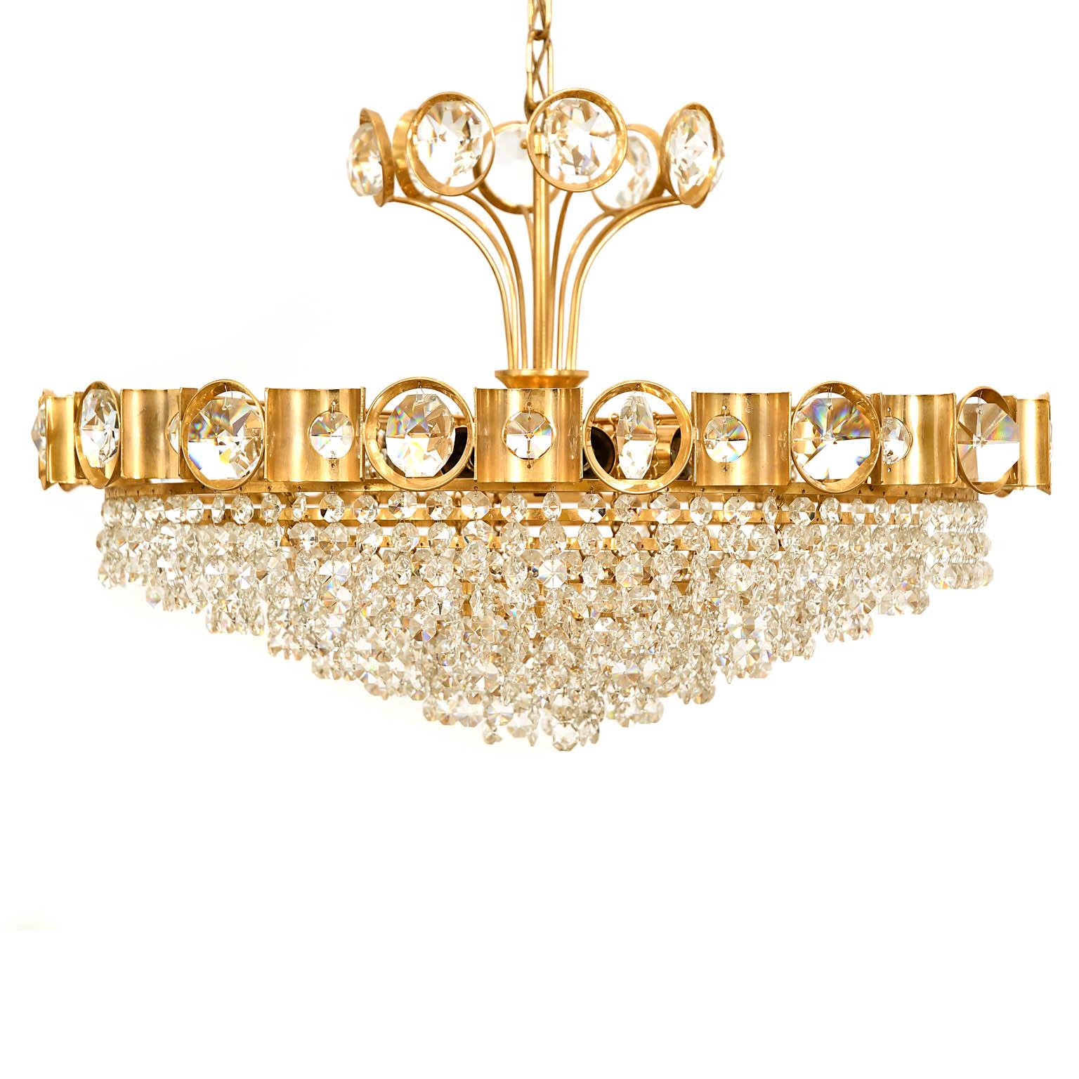 Gilt brass frame, with eight rows of faceted crystals and a final brass loop row. The chandelier is in a very nice original condition and has been professionally refurbished in our workshop.
Palme & Walter made this piece in 1970. 4 of the crystals