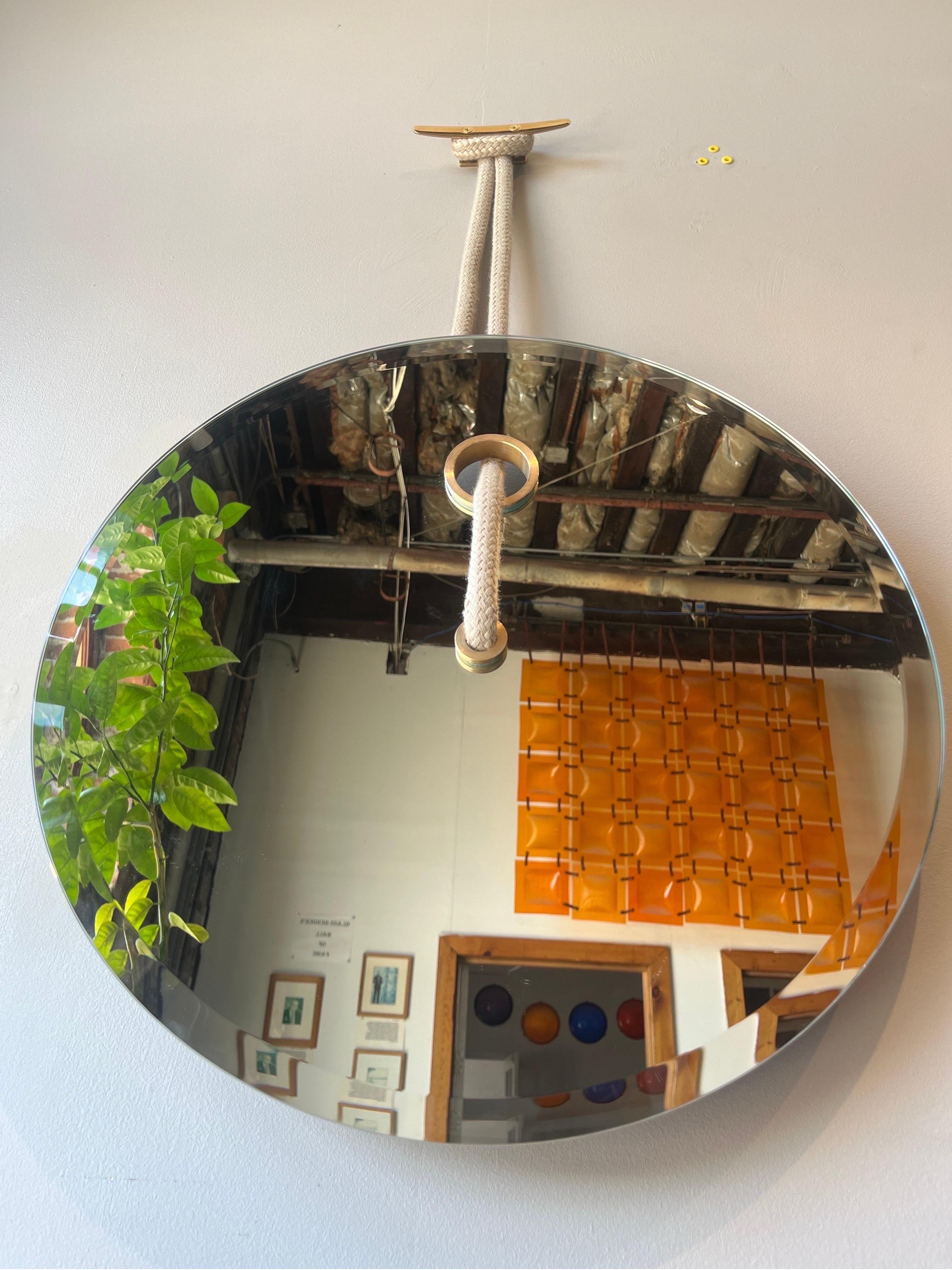 Ce miroir suspendu décoratif nautique allie un design moderne à une élégance intemporelle. Ce miroir décoratif est fabriqué à la main à partir d'un verre de haute qualité et est rehaussé d'une quincaillerie en laiton et d'une ligne de voile antique.