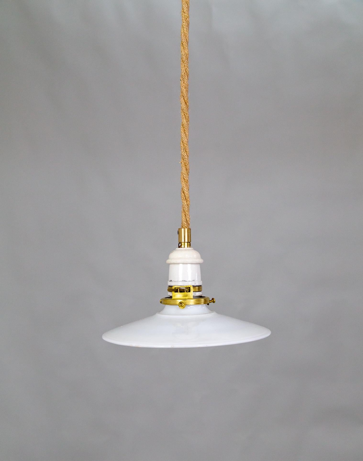 Una lampada a sospensione contemporanea con un cavo rivestito in corda, un piccolo paralume in vetro latte e un baldacchino in ceramica e ottone.  Lunghezza del Corde personalizzabile. 68