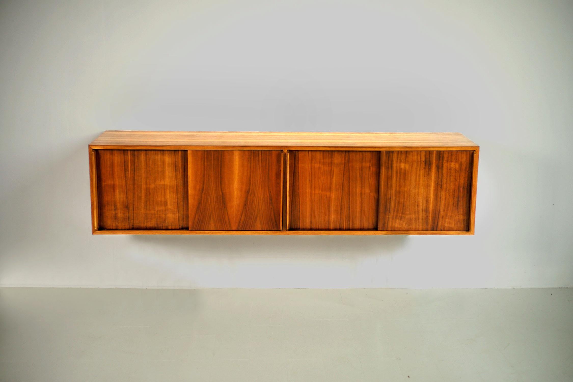 Suspended sideboard in blond flamed walnut, Italy 1955. Equipped with 4 sliding doors with large handles, a central shelf, this beautiful sideboard was part of the furniture of the first apartment-hotel founded in Ventimiglia in 1955. Equipped with