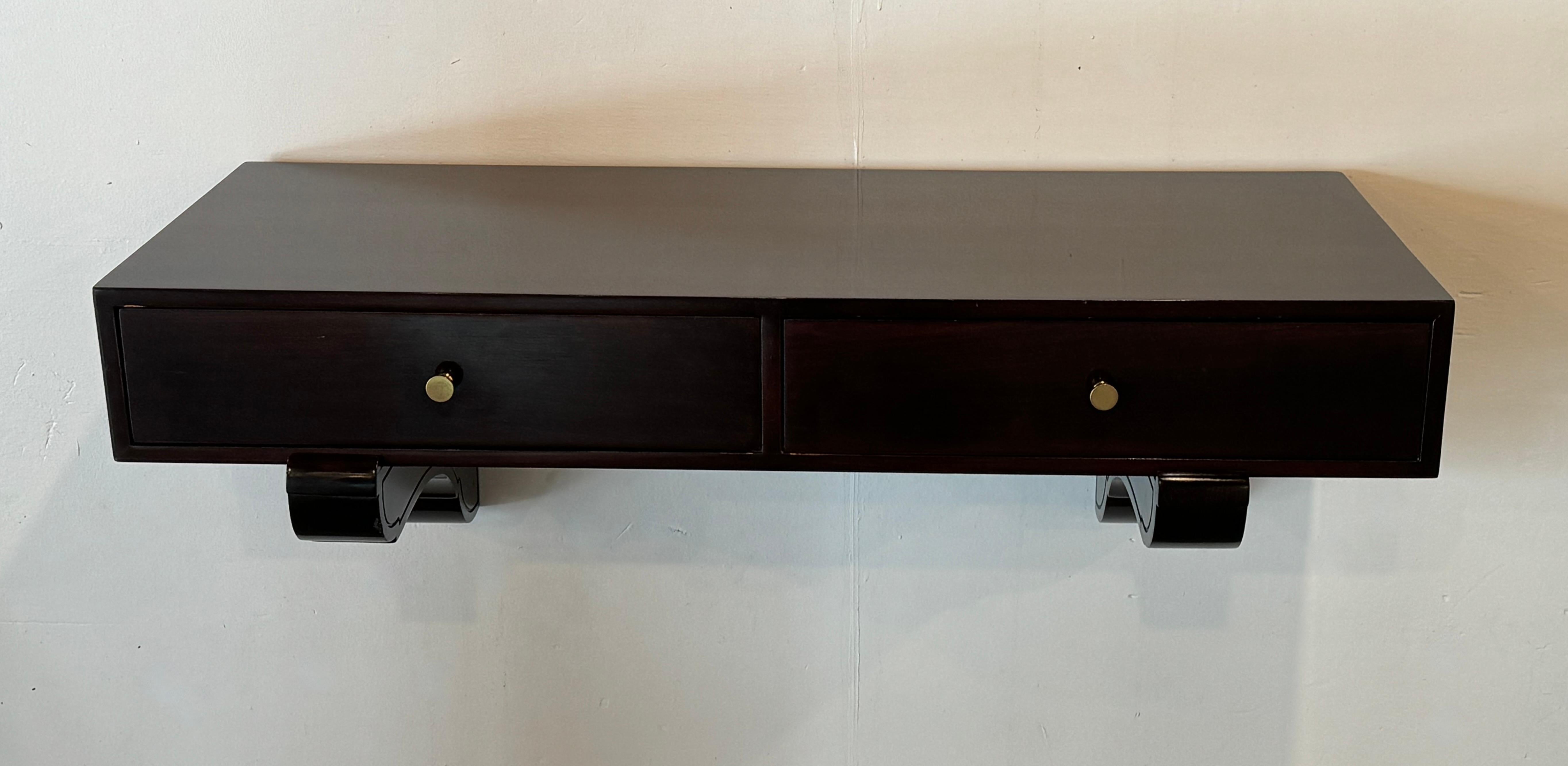 Hanging cabinet attributed to Milo Baughman for Directional furniture, Crafted out of Philippine Mahogany with a dark rosewood finish. The cabinet has two drawers with brass pulls and rests on two stylized wall mounts. An uncommon design by this