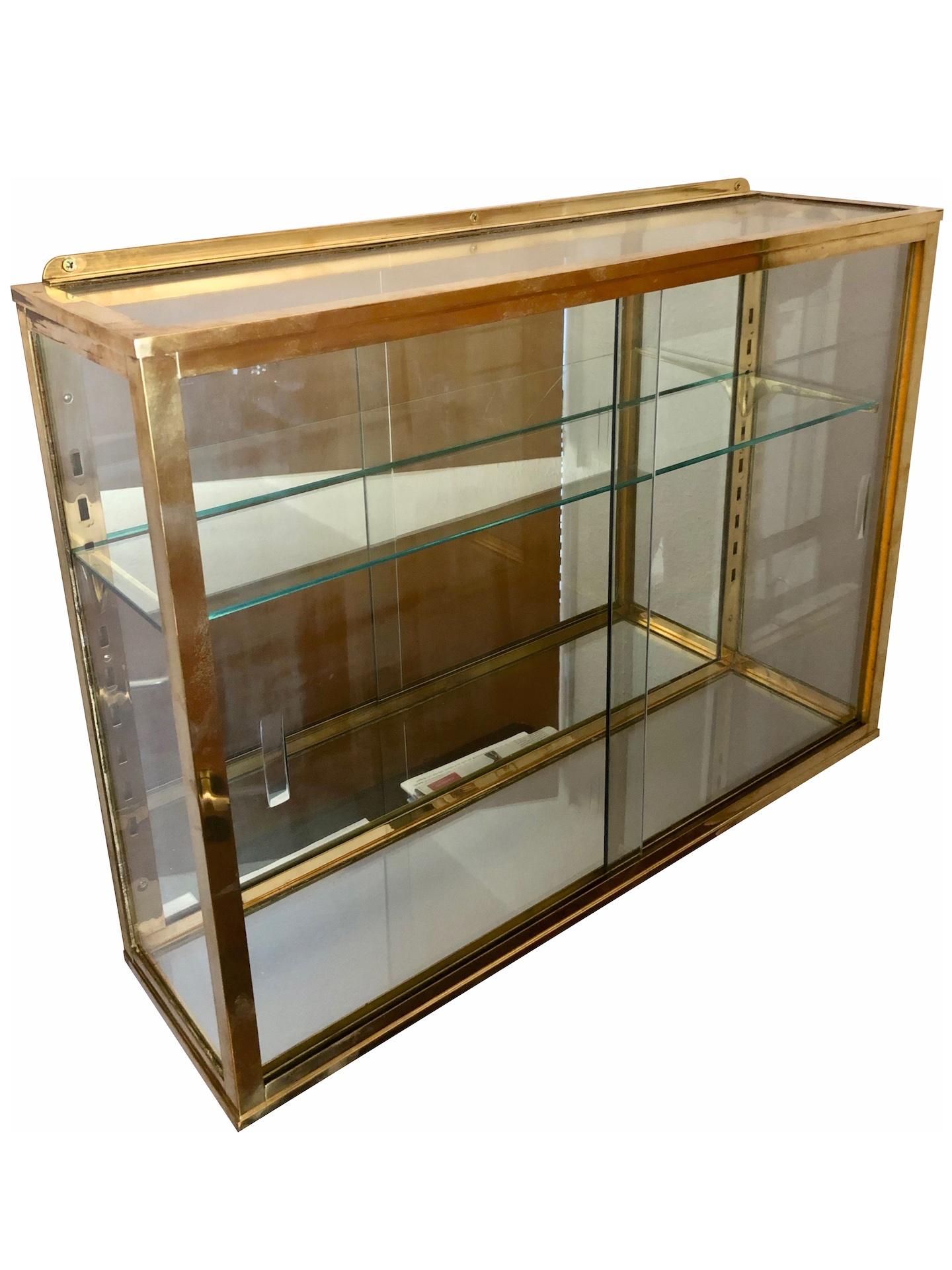 Hanging wall vitrine for collection objects in brass 
One shelf, height adjustable 
France, 1940s
Original patina (just cleaned, not polished)

Dimensions:
Width: 75.5 cm
Height: 55 cm
Depth: 20 cm.