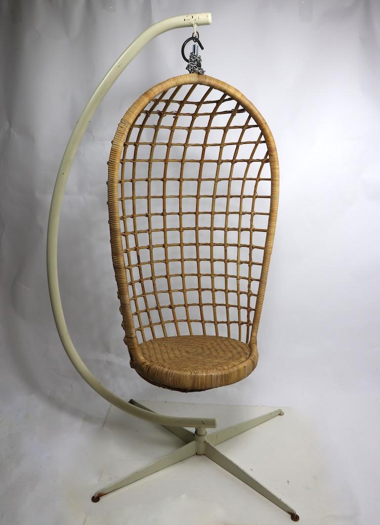 Groovy hanging wicker egg chair with heavy cast iron and steel base. The wicker chair hangs from a coil spring giving it flex when you sit. It comes with additional chain and hook if you choose to hang it from the ceiling rather than the metal