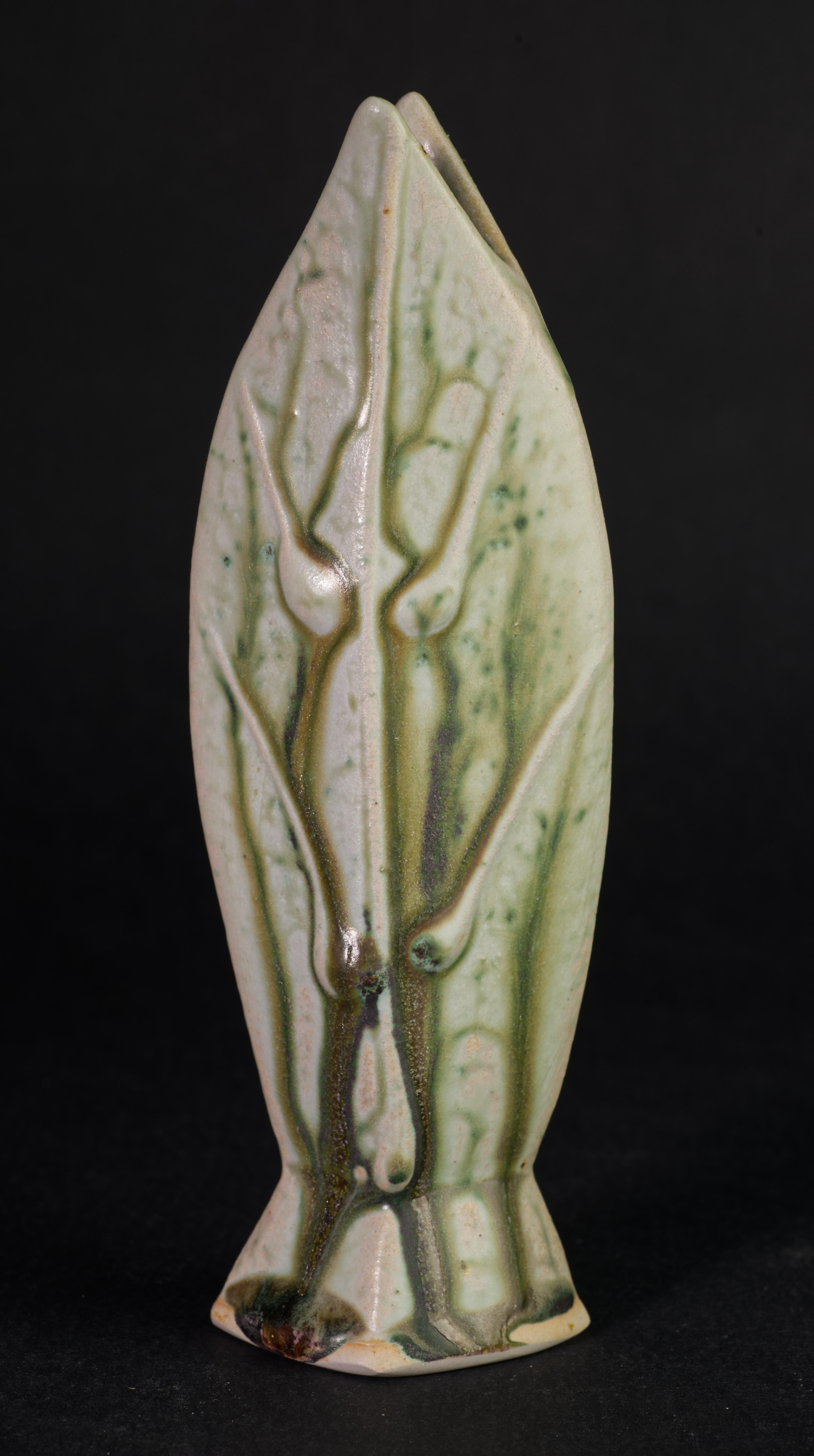  Il vaso a bocciolo curvo figurativo Organic Modern è modellato a mano e smaltato con una combinazione di smalti color cenere e a goccia; la tavolozza di colori celadon, oliva e verde bosco completa la forma minimale del pezzo. L'opera è firmata a