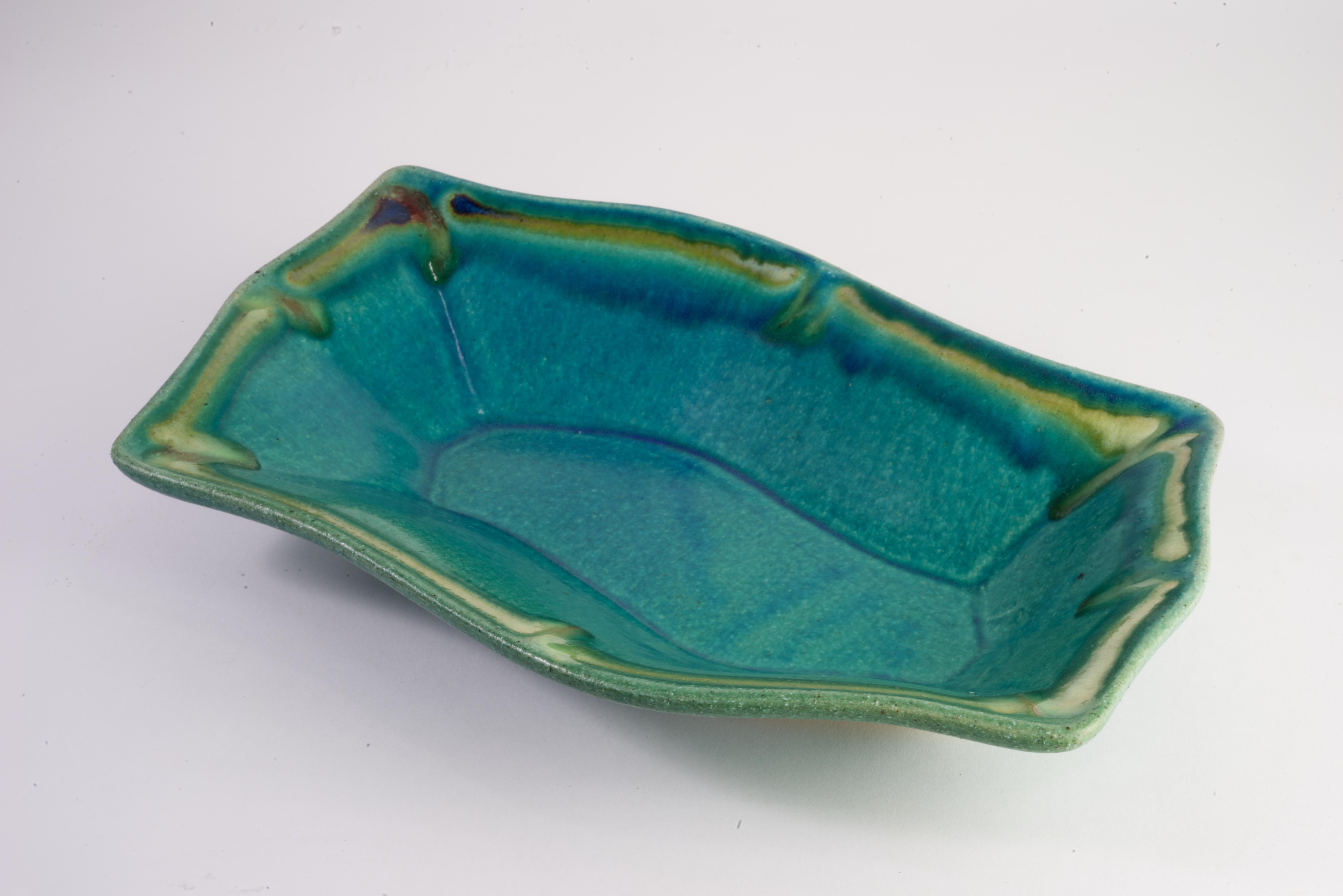  Organic Modern curved bowl is hand-formed and glazed with combination of ash and drip glazes; restrained teal, brown, and pale green palette complements the minimal shape of the piece. The bowl is signed on the bottom by Hank Goodman stamp.

Hank