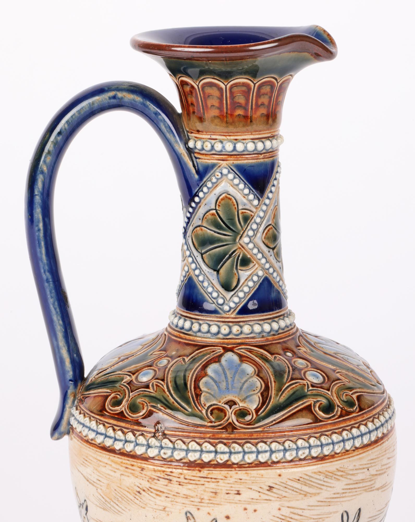 A rare and elegant Doulton Lambeth art pottery ewer decorated with a continuous landscape with a stag and deer by renowned artist Hannah B Barlow and dating from around 1895. The stoneware ewer stands on a narrow skirted foot with a round bulbous