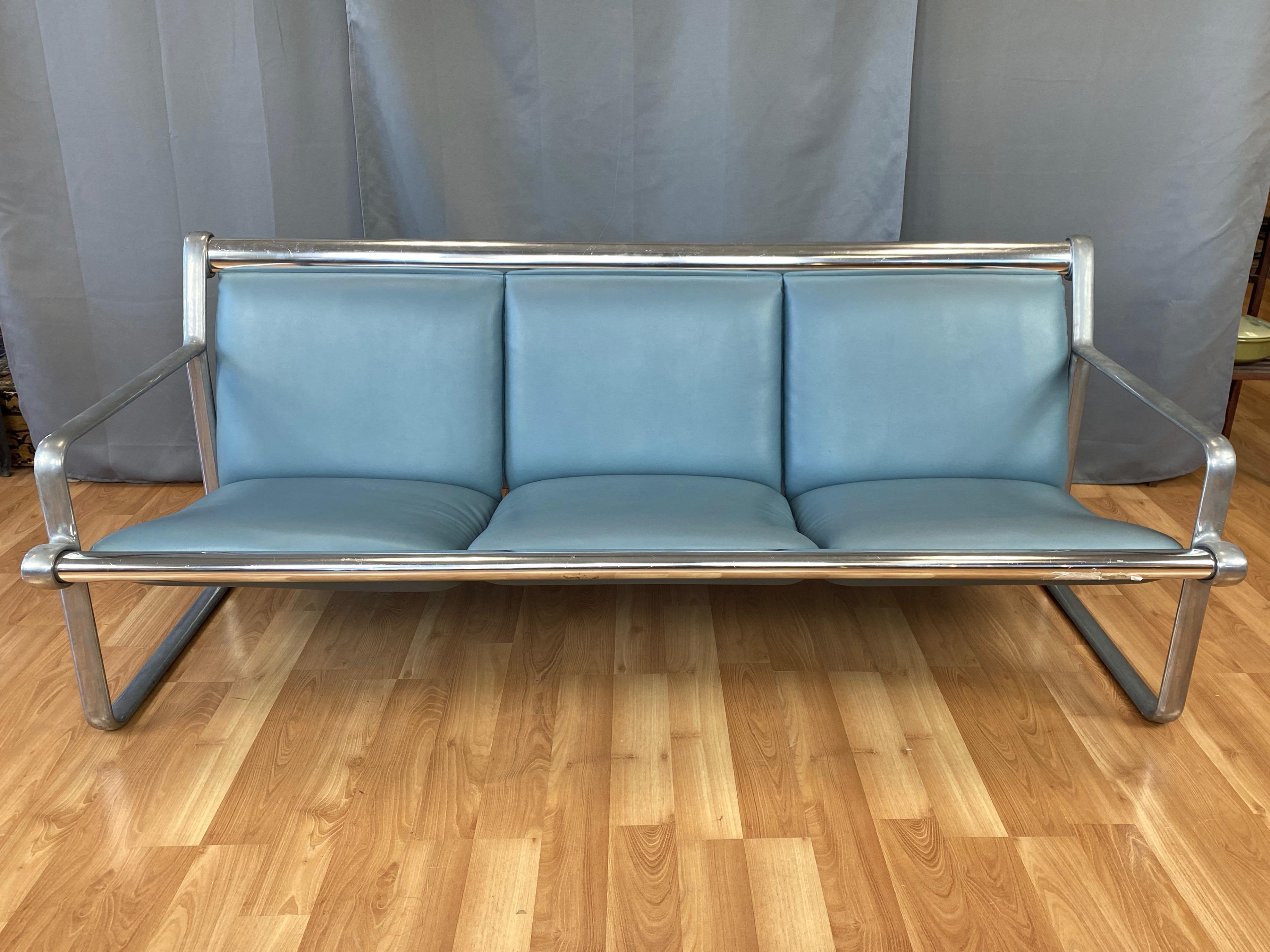 A 1971 Knoll International aluminum three-seat sling sofa by Bruce Hannah and Andrew Morrison.

Minimalist and sleek cast aluminum frame, with satin finish open arm sides connected by a pair of polished full-length cross pieces. Three independent