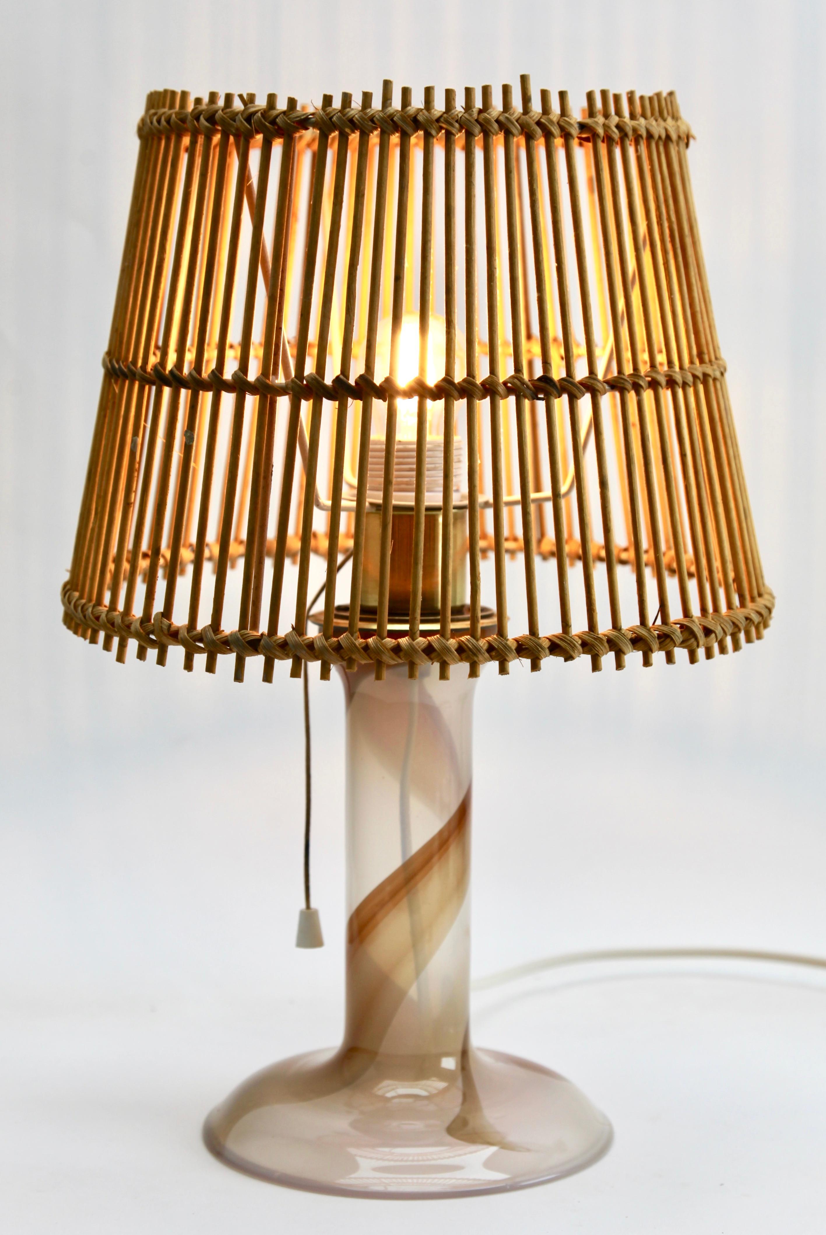 This restrained modern table lamp designed by Hannelore Dreutler at the Lyktan Studio has a semi opaque glass body with a sandy pink hue, incorporating a spiral ribbon rising up the stem, and a flared base to provide stability. 
Made by the