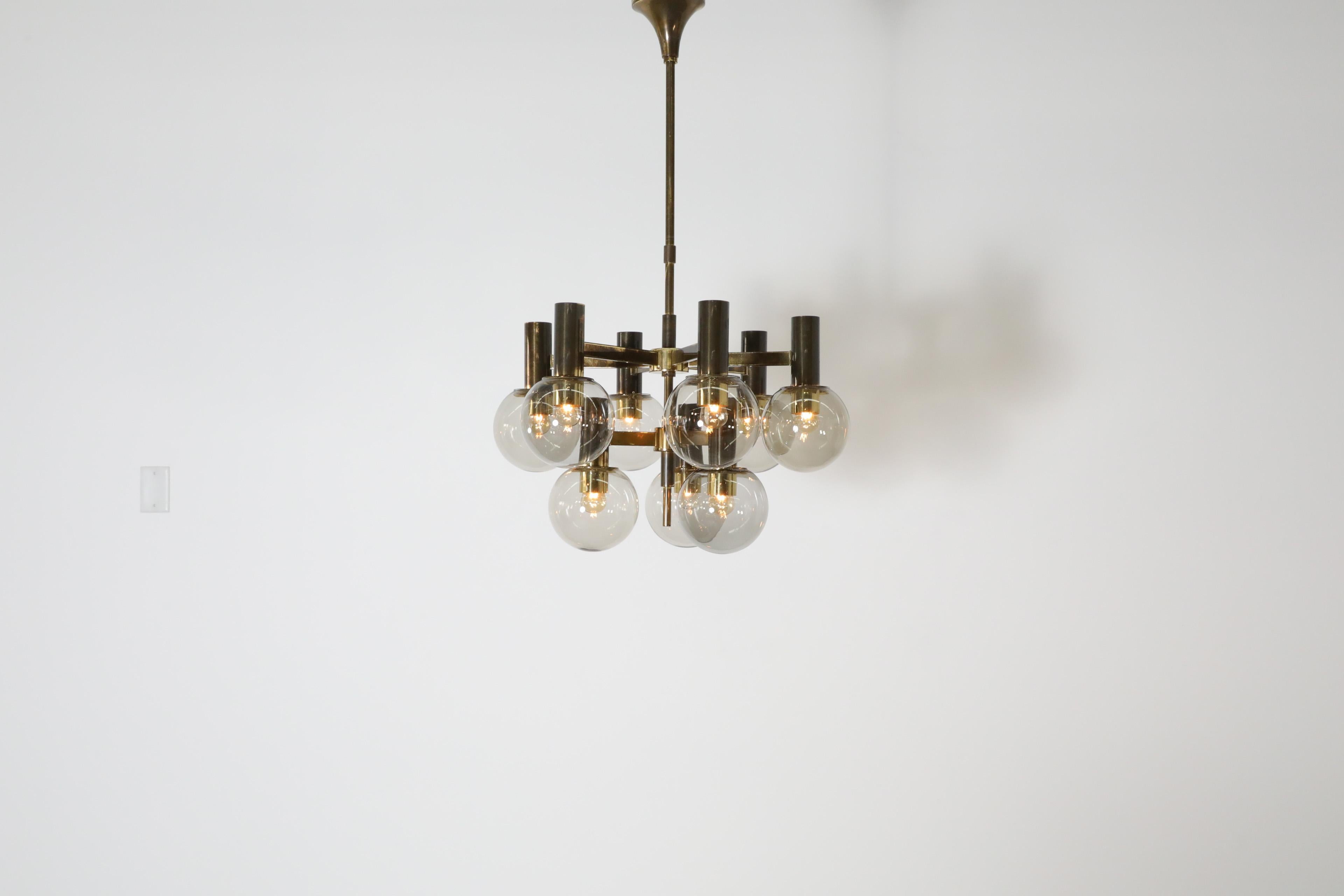 Gorgeous Mid-Century multi-armed chandelier in the style of Hans Agne Jacobssen. An elegant multi-armed chandelier with 9 smoked glass globe shades and brass fixtures. A perfect chandelier for complimenting an upscale dining space tying together a
