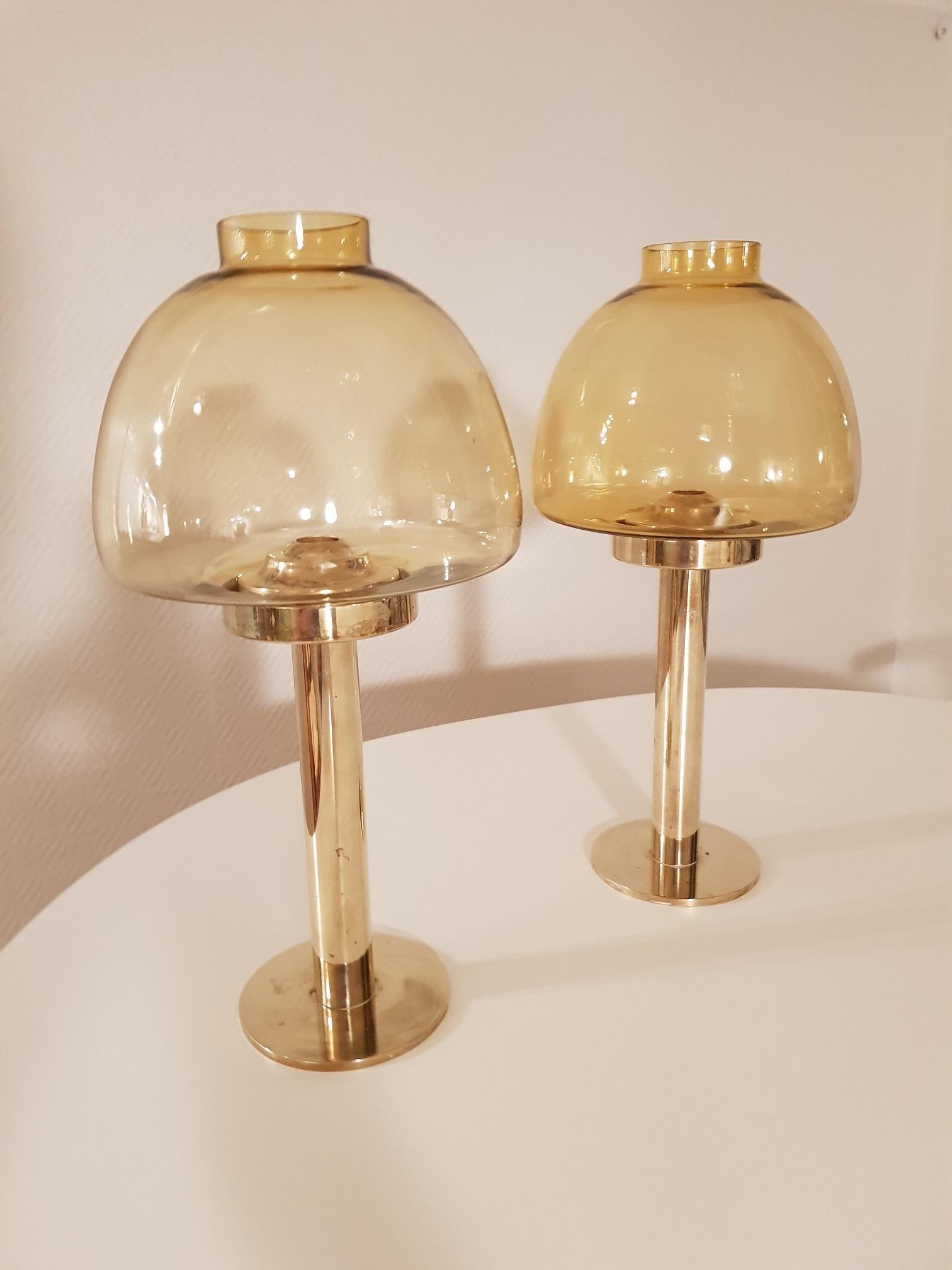 2 vintage candleholders in brass and smoked glass. Produced in the 1960s. Design by Swedish Hans-Agne Jakobsson and produced in Markard in Sweden. The design is made to hold a candle stick at the right and same height all the time. This was a