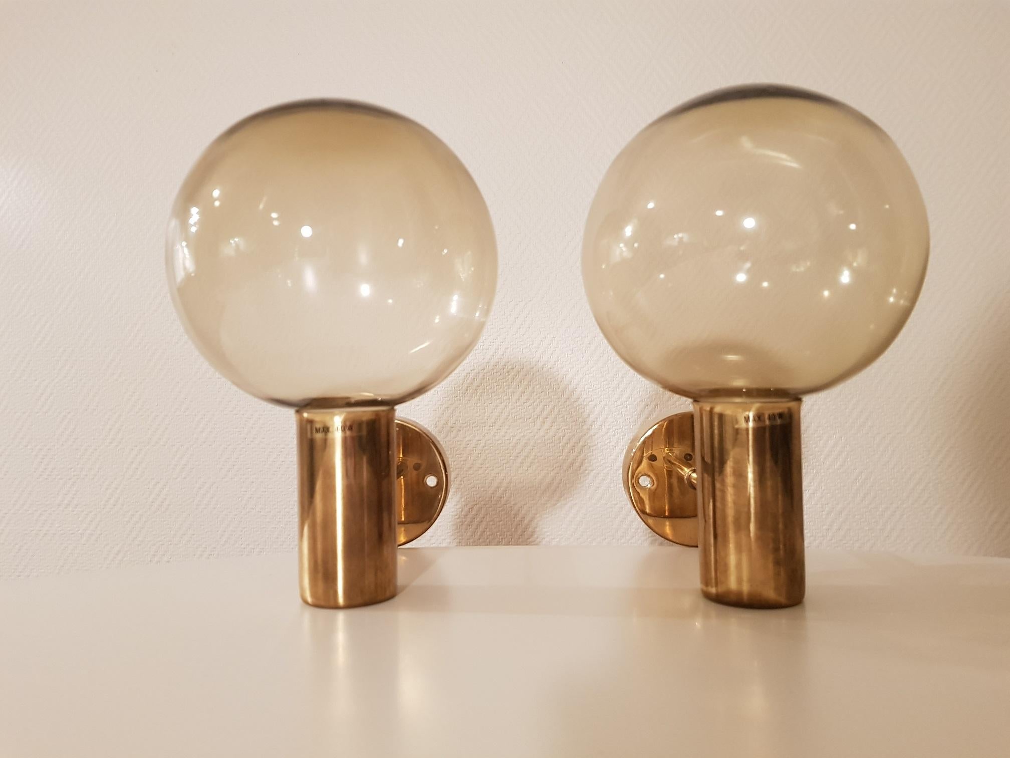 2 vintage wall lamps in brass and smoked glass. Produced in the 1960s. Made in Sweden by Hans-Agne Jakobsson AB in Markaryd. Designed by the famous Swedish designer Hans-Agne Jakobsson. The wall lamps are named model V149.