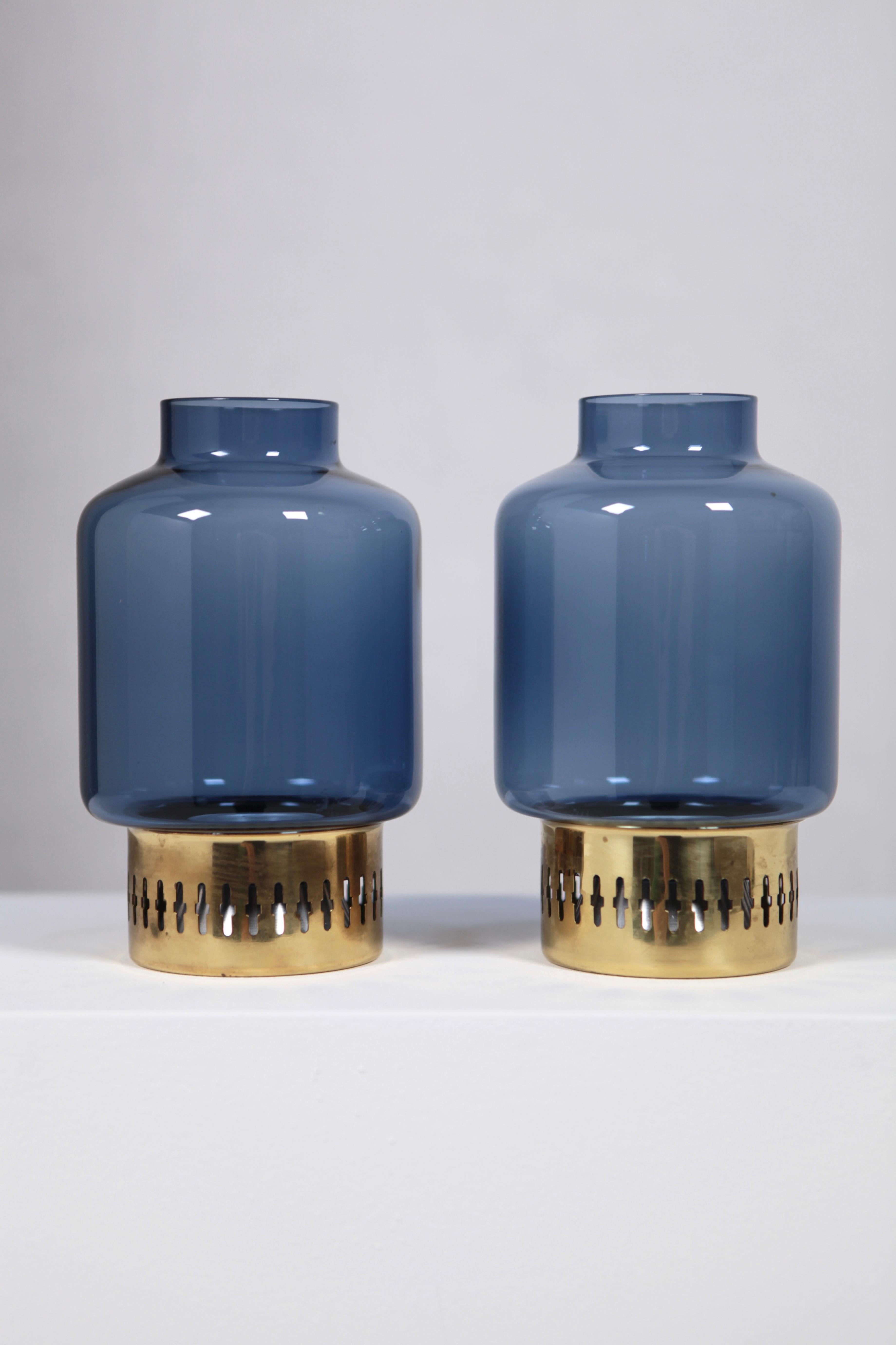 A nice set of 2 brass and colored blue glass candleholder by Hans-Agne Jakobsson, Sweden, 1950s. Great condition, no chips to the glasses, no dents to the brass. Signed to the underside.