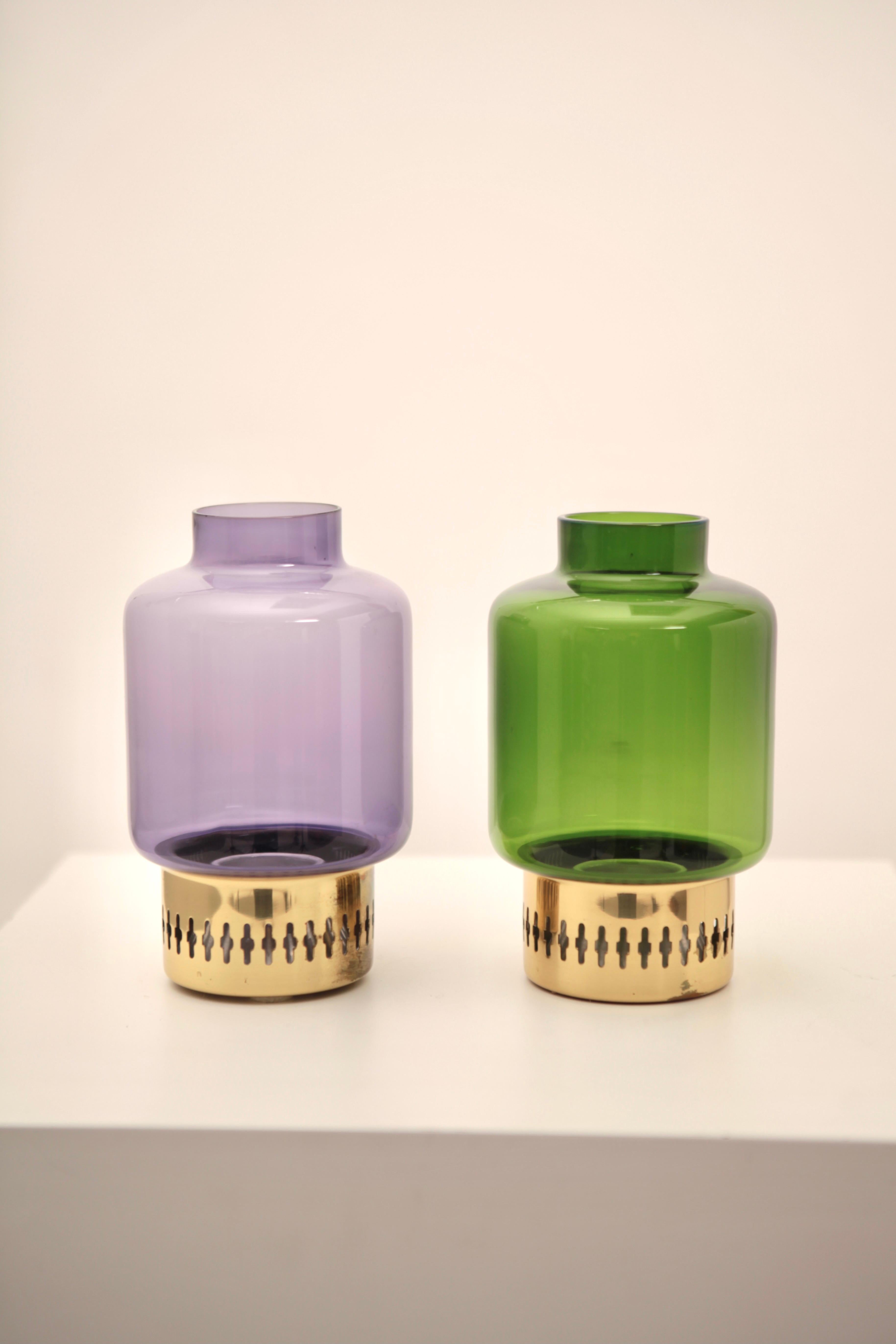 A nice set of 2 brass and colored purple & green glass candleholder by Hans-Agne Jakobsson, Sweden, 1950s. Purple glass has chip to the rim, but not visible when stuck on the brass holder, no dents to the brass. Signed to the underside.