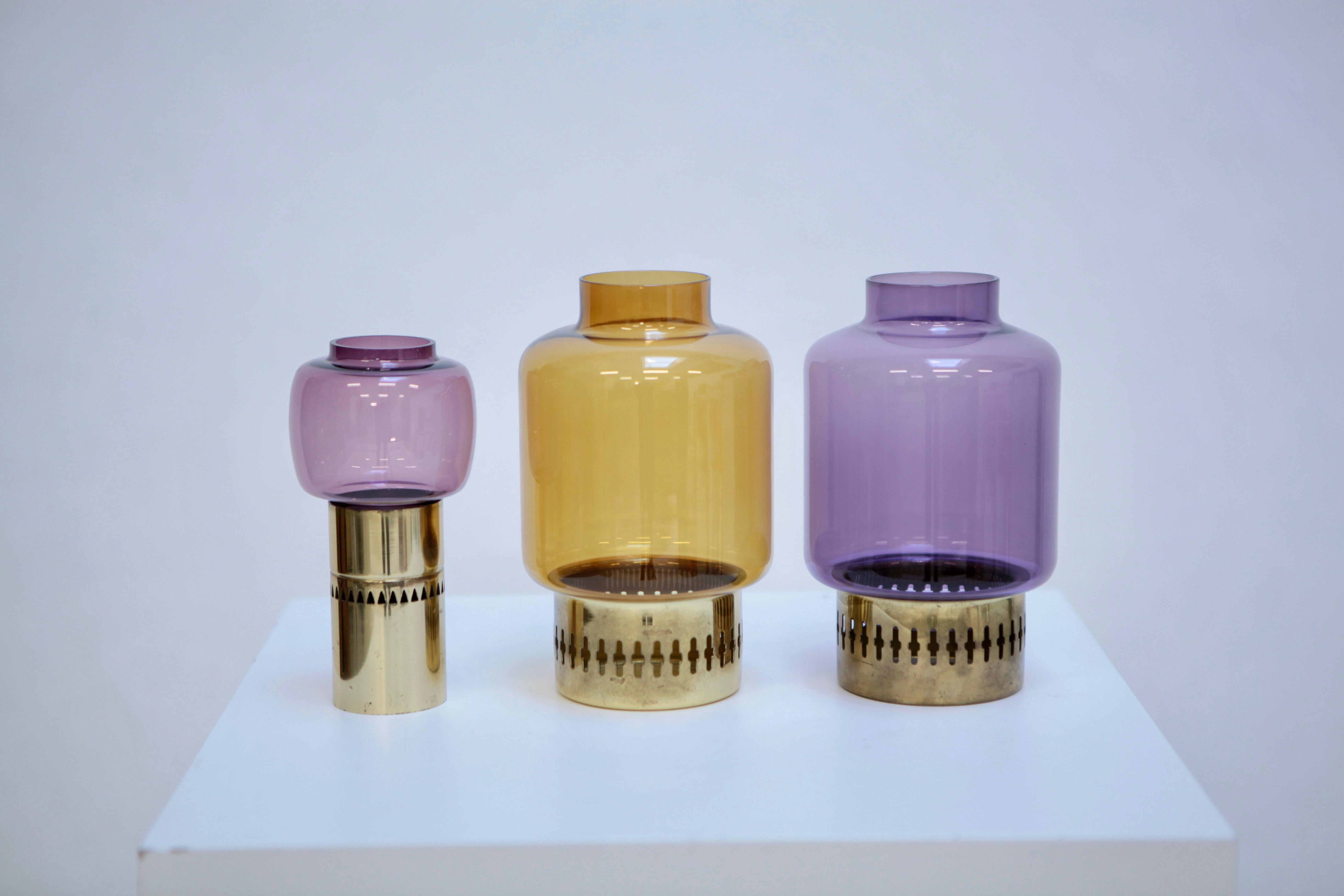 A nice set of 2 brass and colored purple & green glass candleholder by Hans-Agne Jakobsson, Sweden, 1950s. Purple glass has chip to the rim, but not visible when stuck on the brass holder, no dents to the brass. Signed to the underside.