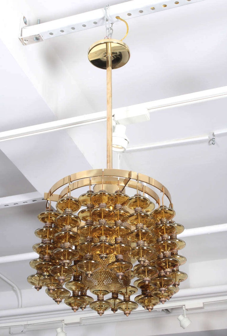 Scandinavian Modern pendant chandelier made from two rows of amber glass orbs on a brass frame. Glass body measures 11.5