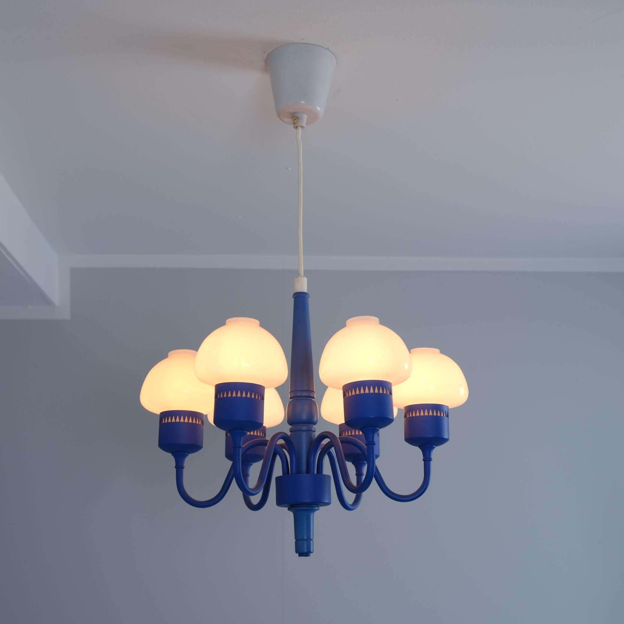 Un bellissimo lampadario blu e bianco realizzato dall'importante designer svedese Hans-Agne Jakobsson. La lampada è composta da una parte centrale in legno dipinto di blu con sei bracci in metallo blu che terminano con un nido triangolare perforato