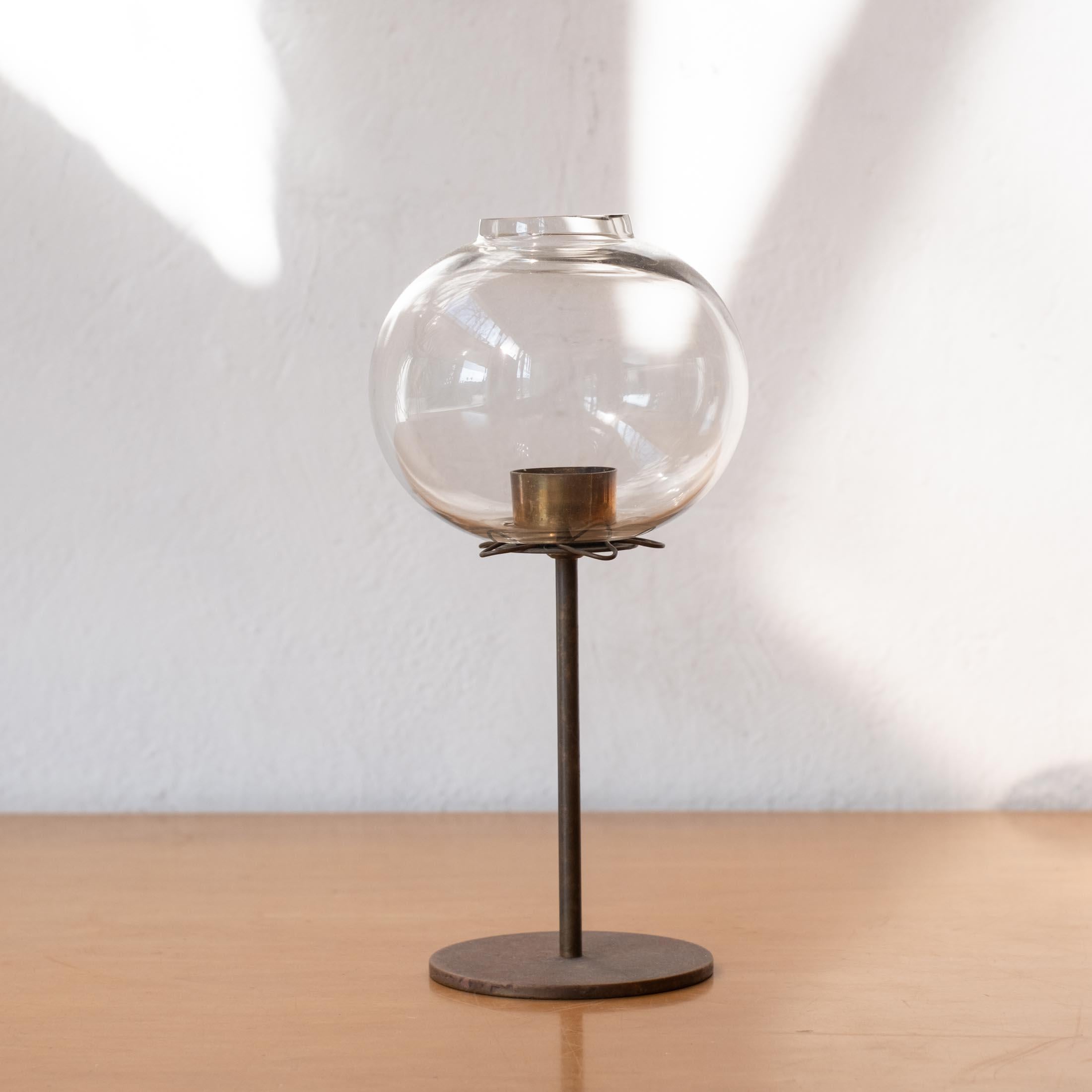 Candle holder designed by Hans Agne Jakobsson. It was produced by his own company, Hans Agne Jakobsson A. B. in Markaryd, Sweden. Solid brass with a wonderful patina and a hand blown glass shade. It also retains the often missing undulating star