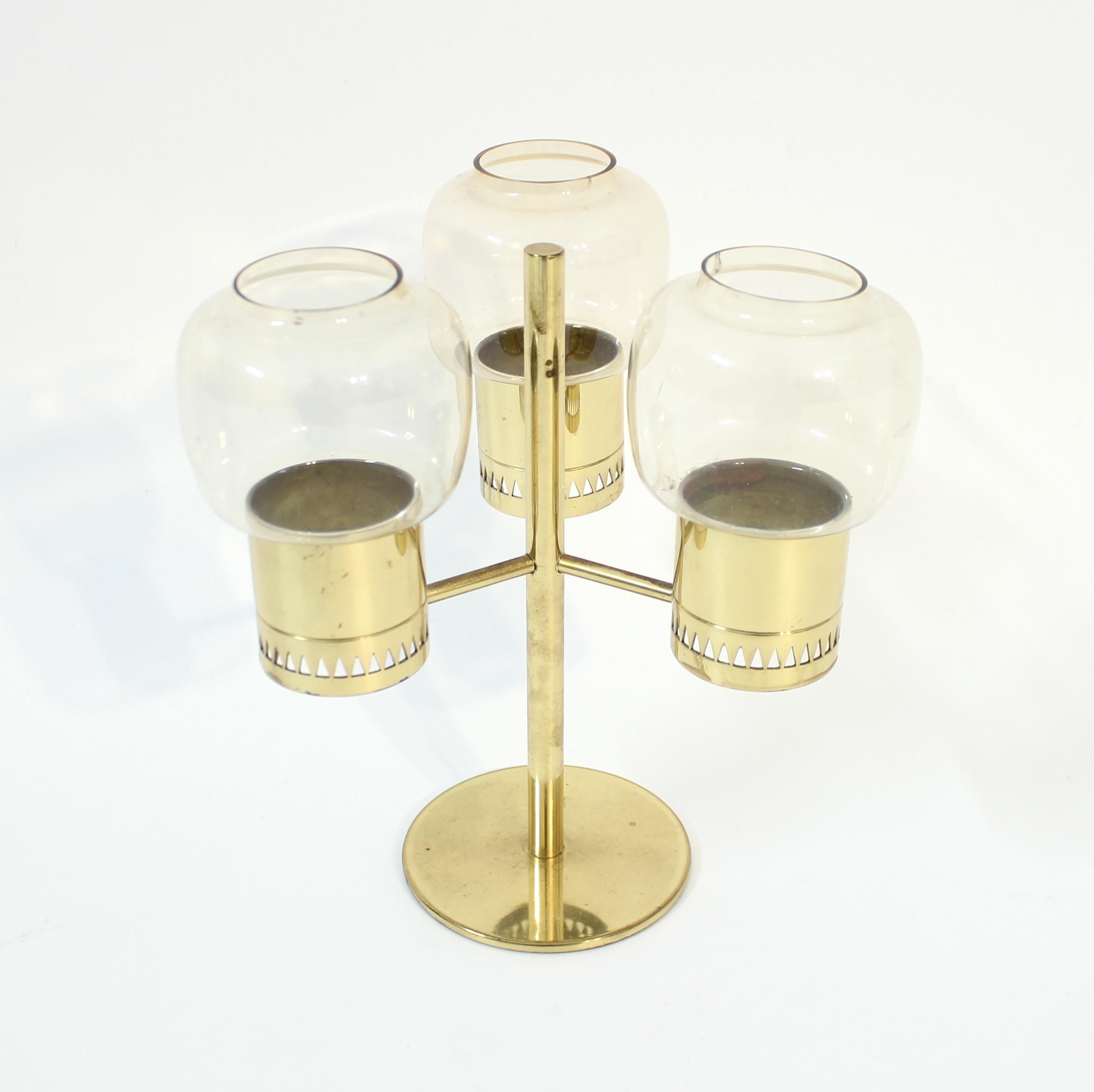 Candle holder for three candles, model L-67, designed by Hans-Agne Jakobsson for his own company  Hans-Agne Jakobsson AB in the 1960s. It contains three clear / smoke coloured glass bulbs on a brass base. Very good vintage condition with light ware