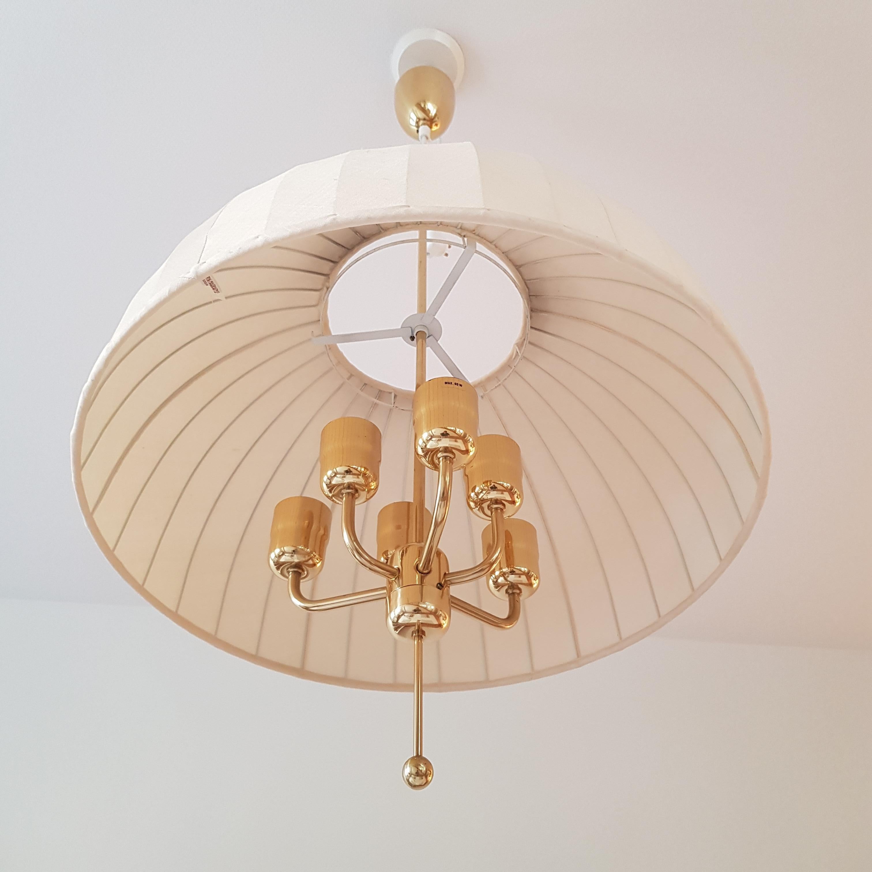 Large, six-armed Scandinavian Modern pendant lamp, Model “T549/6”, designed by Hans Agne Jakobsson and produced by AB Markaryd in the 1960s. Frame in brass and the shade in the original off-white fabric.

Original labels intact on both the ceiling