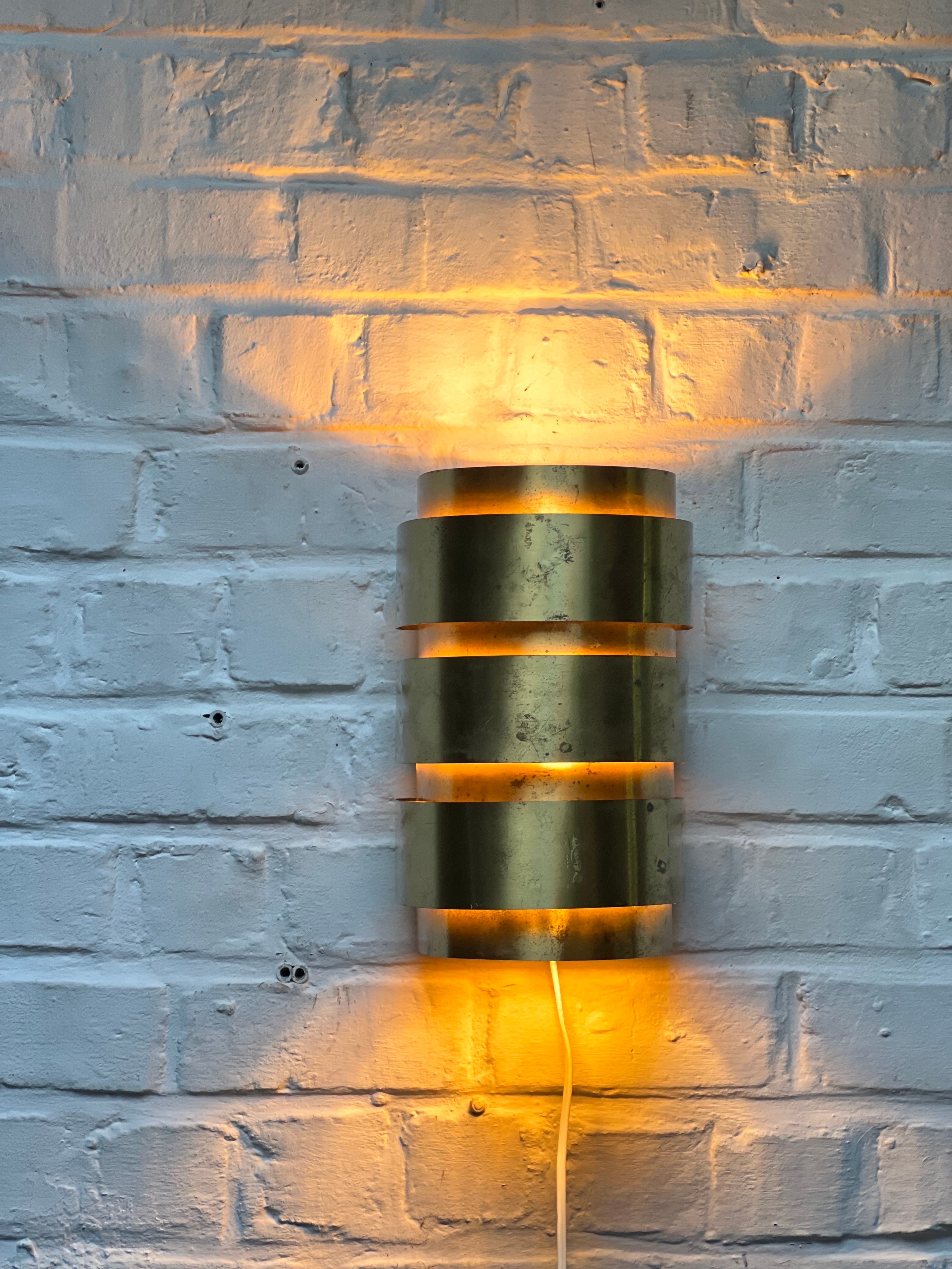 Nice brass wall lamps. They provide a warm atmosphere and even better when lighted. Made of thin stripes of brass delicately riveted with a brass nail to the metal frame. Minimal details. We have a set of 4 to match this one. Great to have them as a