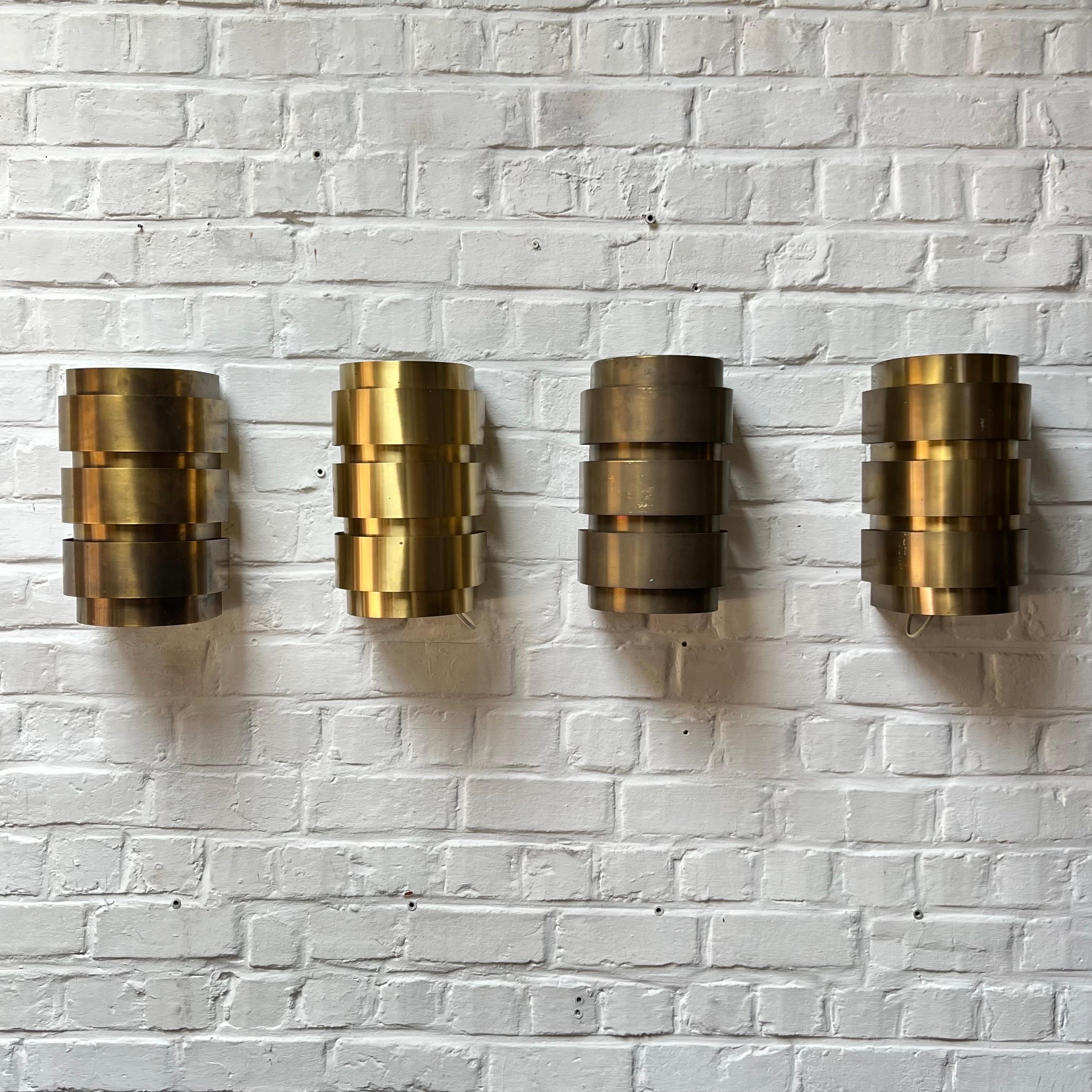Nice set of 4 brass wall lamps. They provide a warm atmosphere and even better when lighted. Made of thin strips of brass delicately riveted with a brass nail to the metal frame. Minimal details. Great to have them as a set of 4 and especially in