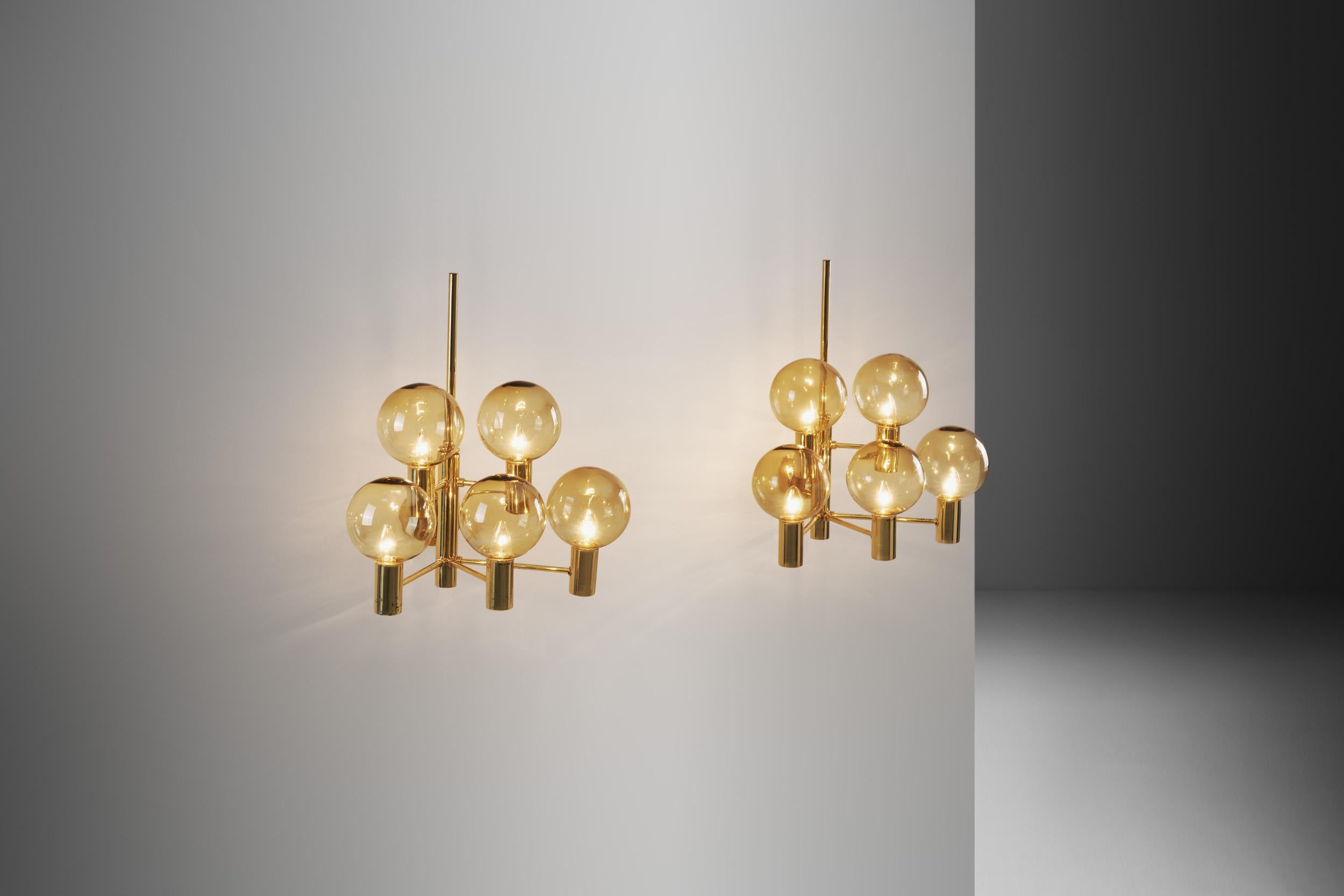 This pair of wall lamps is among the most stunning models of Jakobsson’s. With each brass frame holding five smoked, translucent glass shades, these lamps are the upgraded, larger version of the model V 149/3. The design clearly shows the Swedish