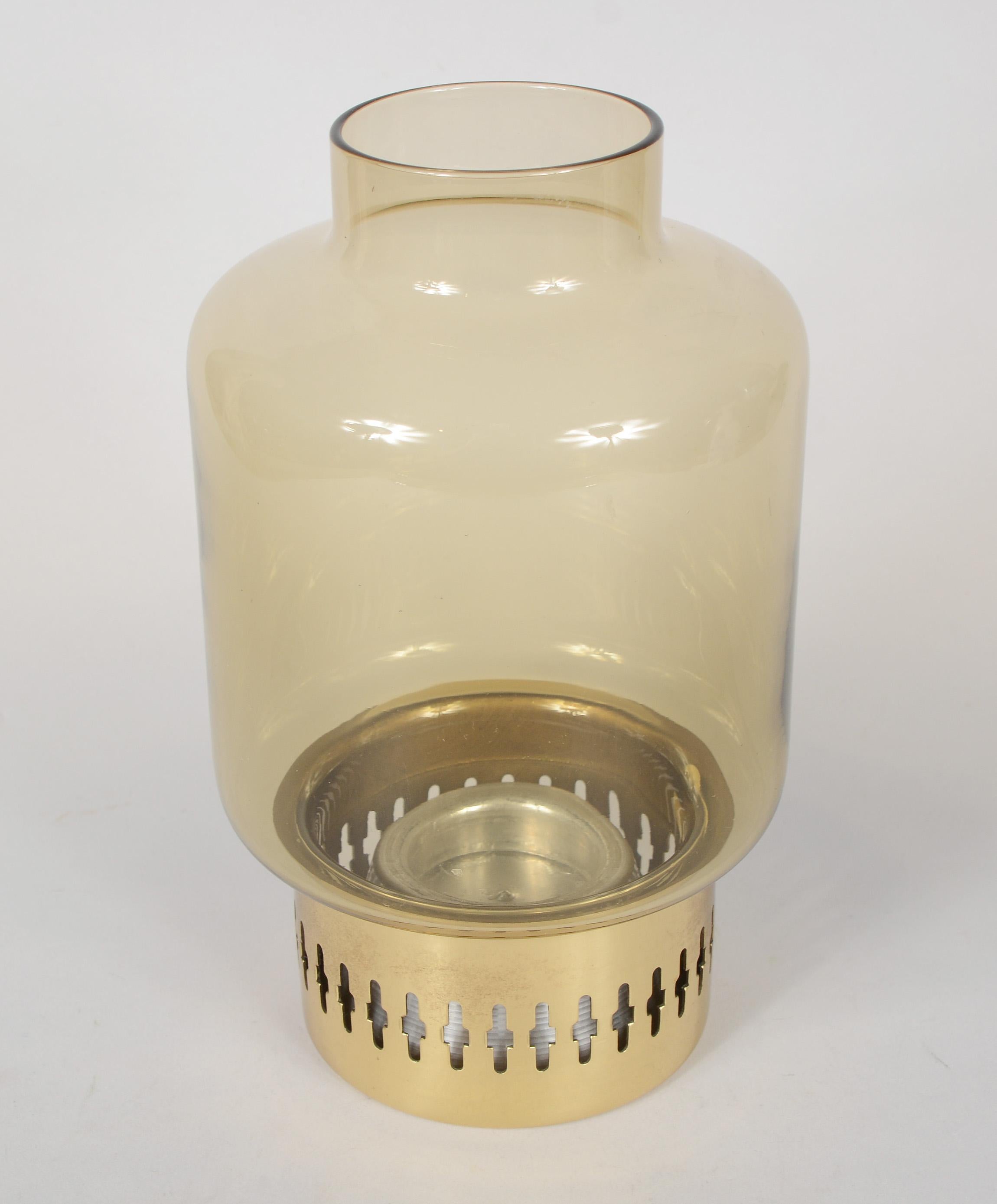 Brass and glass candleholder designed by Hans-Agne Jakobsson. This was made in Sweden by AB Markaryd. This candle holder has a warm smoke colored shade. There is a small dent on the underside of the bottom that is not visible when the holder is