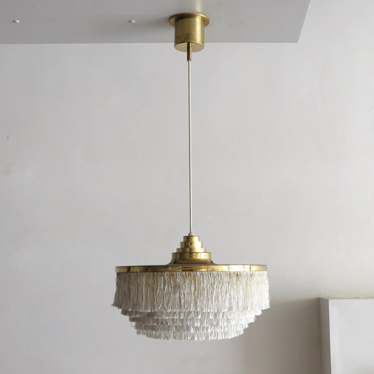 Wonderful pendant lamp by Hans-Agne Jakobsson for Markaryd, Sweden, 1960, with five tiers of off-white fringe silk cord with brass hardware frame and original brass canopy. Overall drop can be customized, wired for US standards, one E27 socket, max.