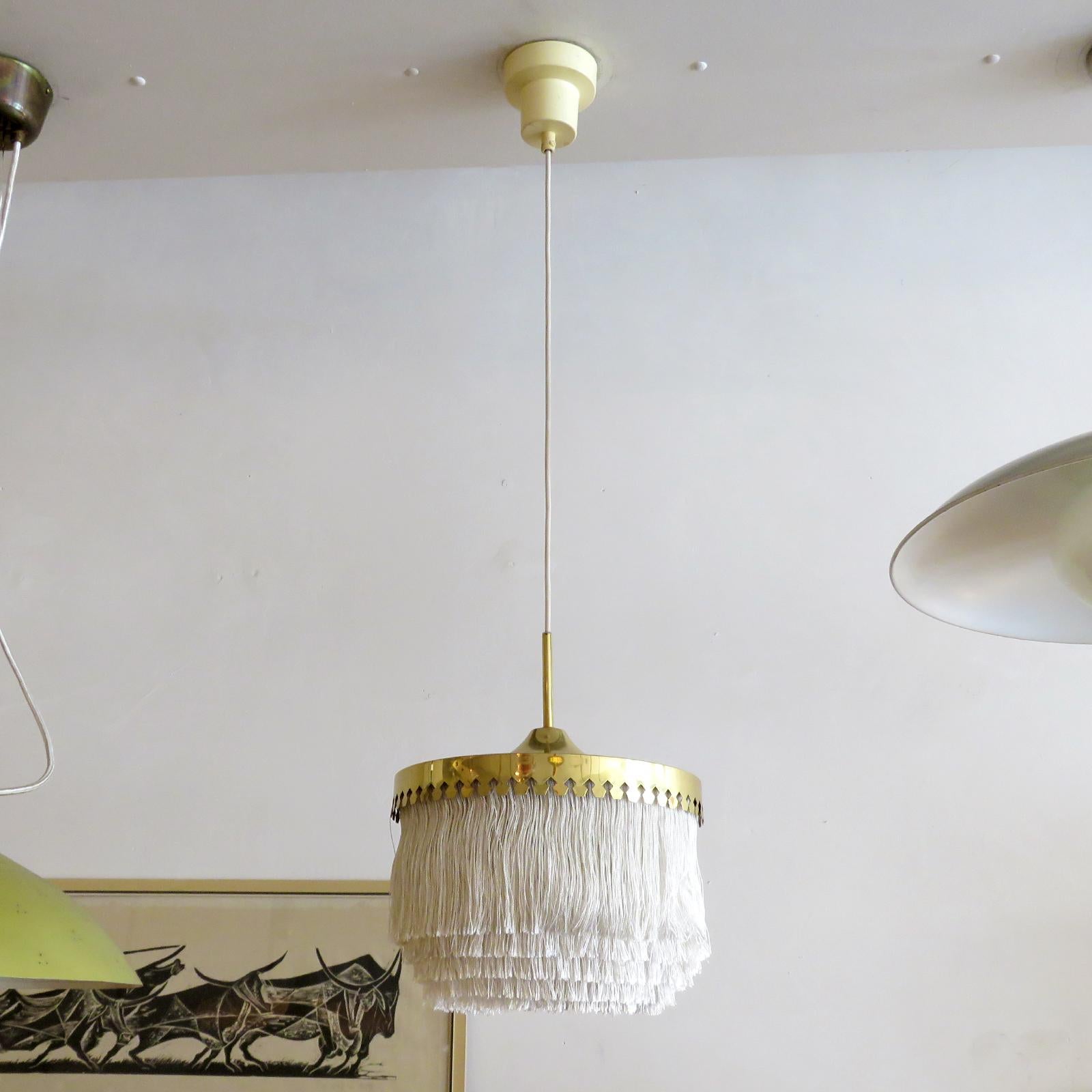 Wonderful pendant lamp by Hans-Agne Jakobsson for Markaryd, Sweden, 1960, with five tiers of off-white fringe silk cord with brass hardware frame and original white canopy. Overall drop can be customized. Custom back plate for US j-boxes, wired for
