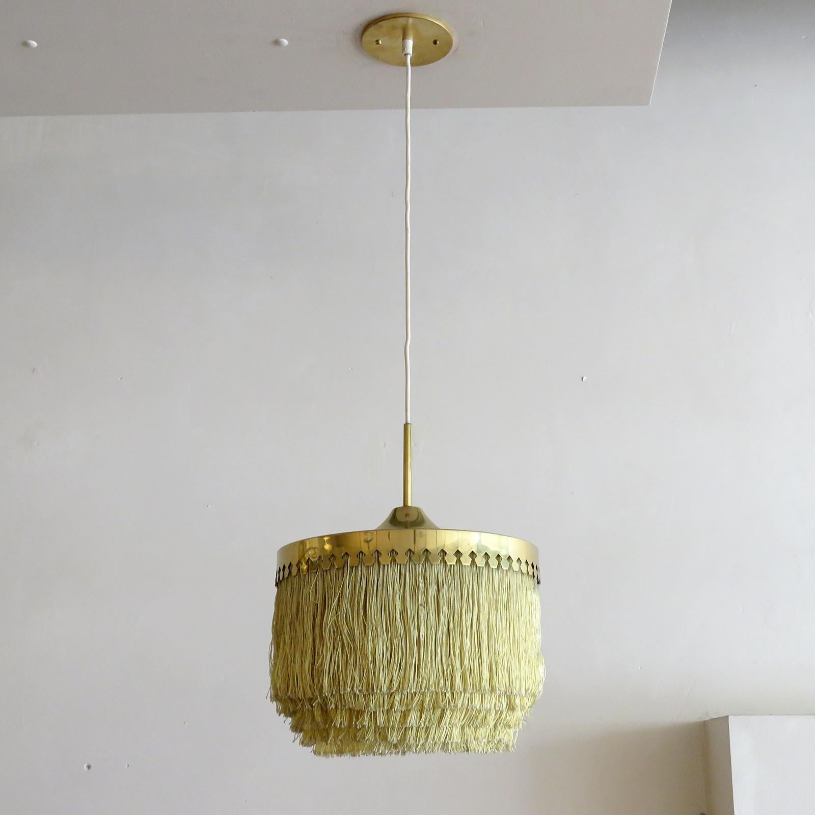 Wonderful pendant lamp by Hans-Agne Jakobsson for Markaryd, Sweden, 1960, with five tiers of off-white fringe silk cord with brass hardware frame and original white canopy. Overall drop can be customized, wired for US standards, one E27 socket, max.